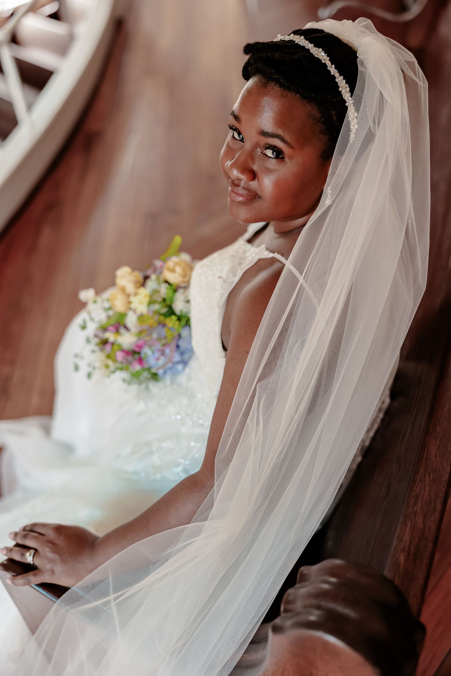 A bride, sitting in a white wedding dress and veil, holds a pastel bouquet. Image by Emily Joy, wedding photographer in Memphis.