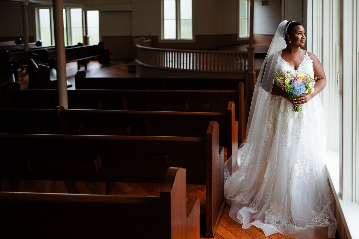 A bride in an elegant gown stands in a Victorian chapel for portrait by Memphis Wedding Photographer Emily Joy Photography