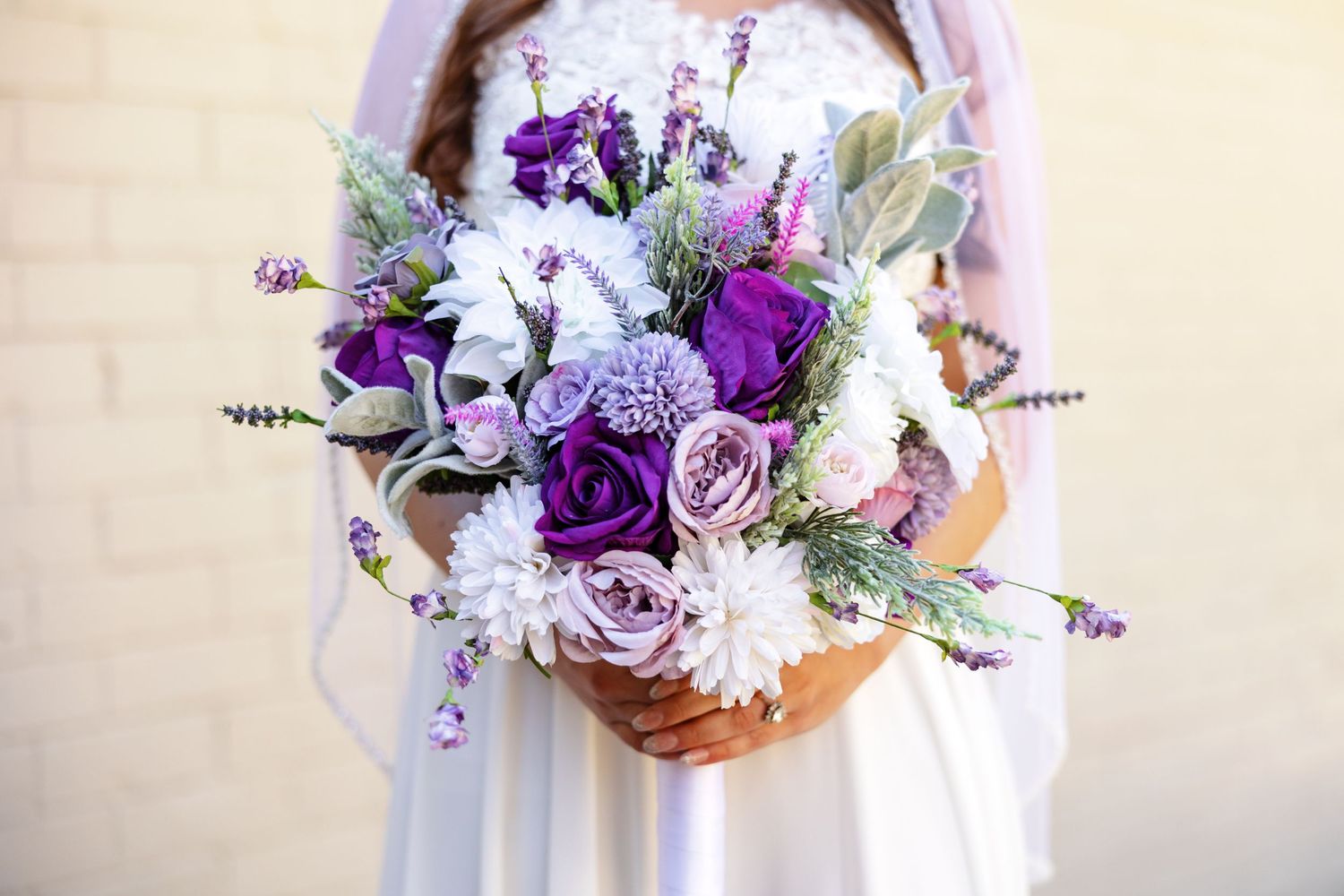 A bride displays her purple, white and green bouquet.