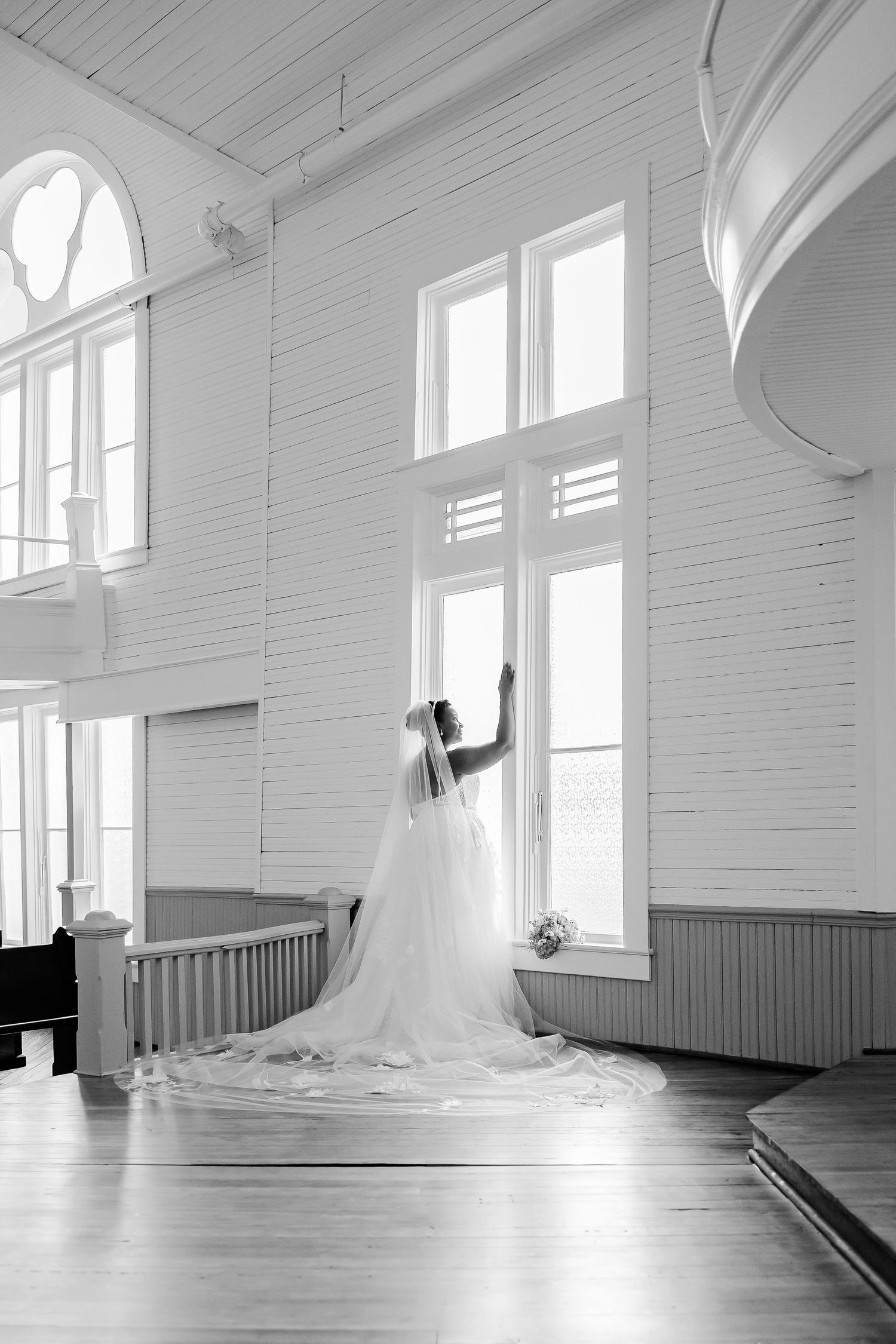 A bride by a window composed into a portrait of a restored Victorian era chapel.  Image by Emily Joy, wedding photographer in Memphis.