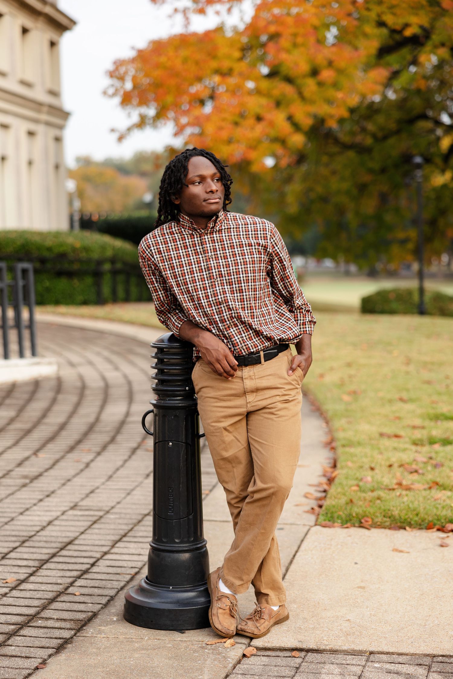 A senior boy leaning against a post in front of the Brooks Museum in Memphis, TN.