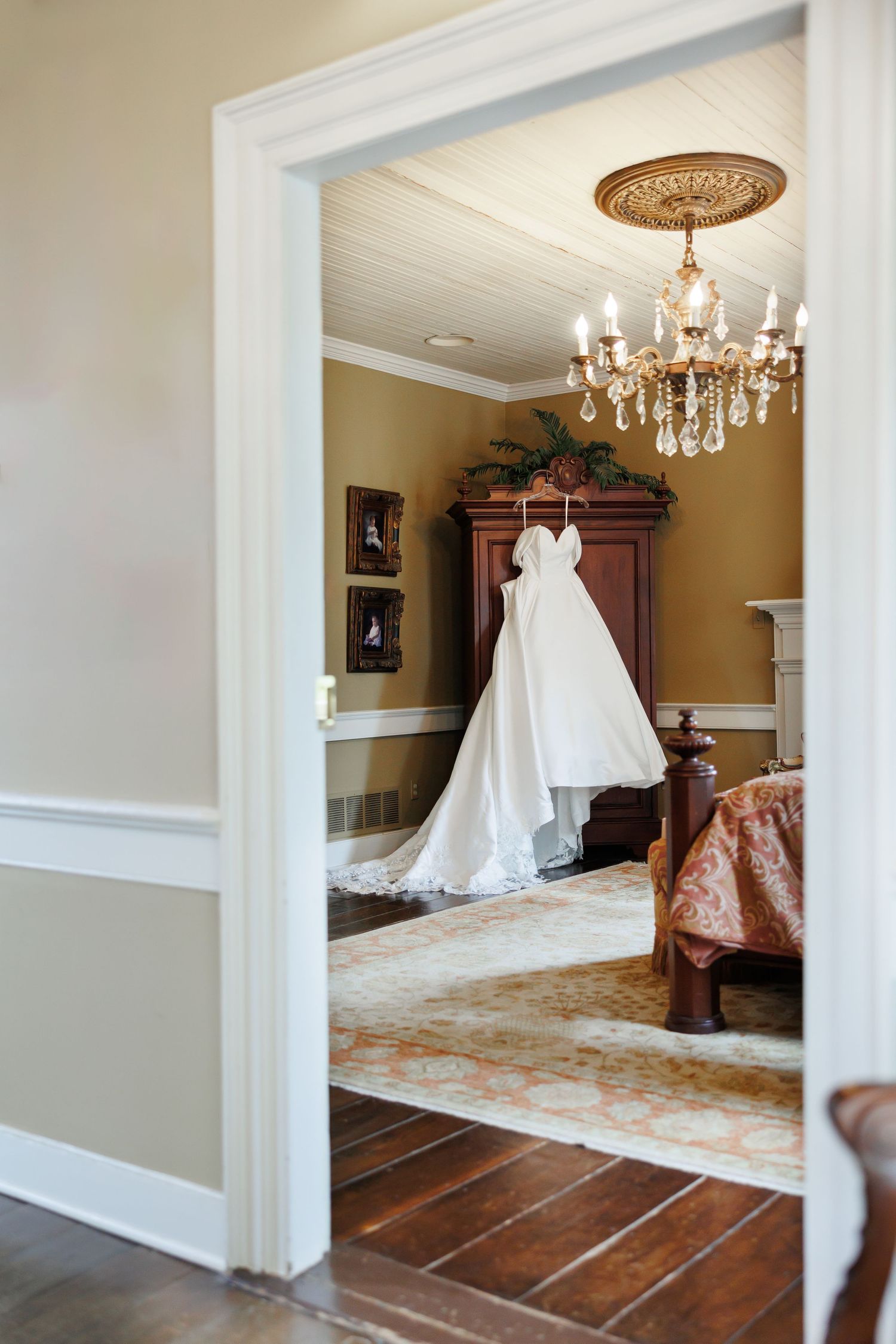 A wedding gown framed in a doorway of a vintage room, adorned with a chandelier.  Image by Emily Joy, wedding photographer in Memphis.