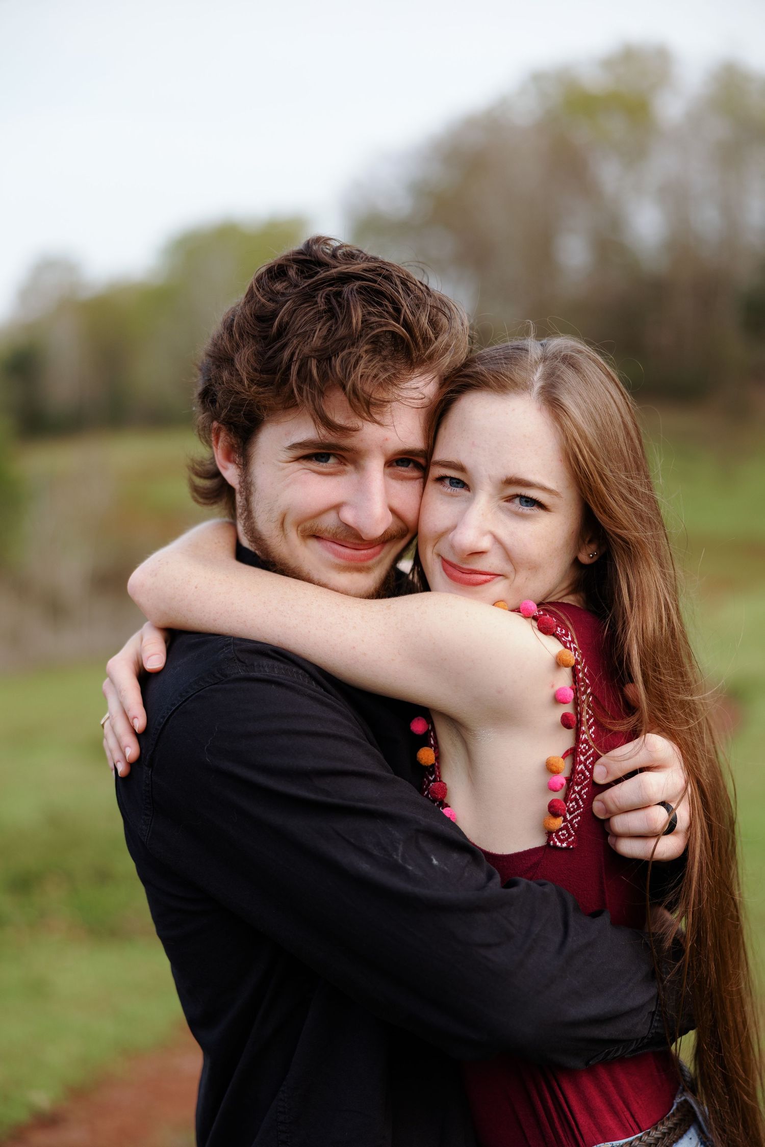 Young couple hugs close and smiles at camera xfor a portrait by Memphis wedding photographer Emily Joy Photography