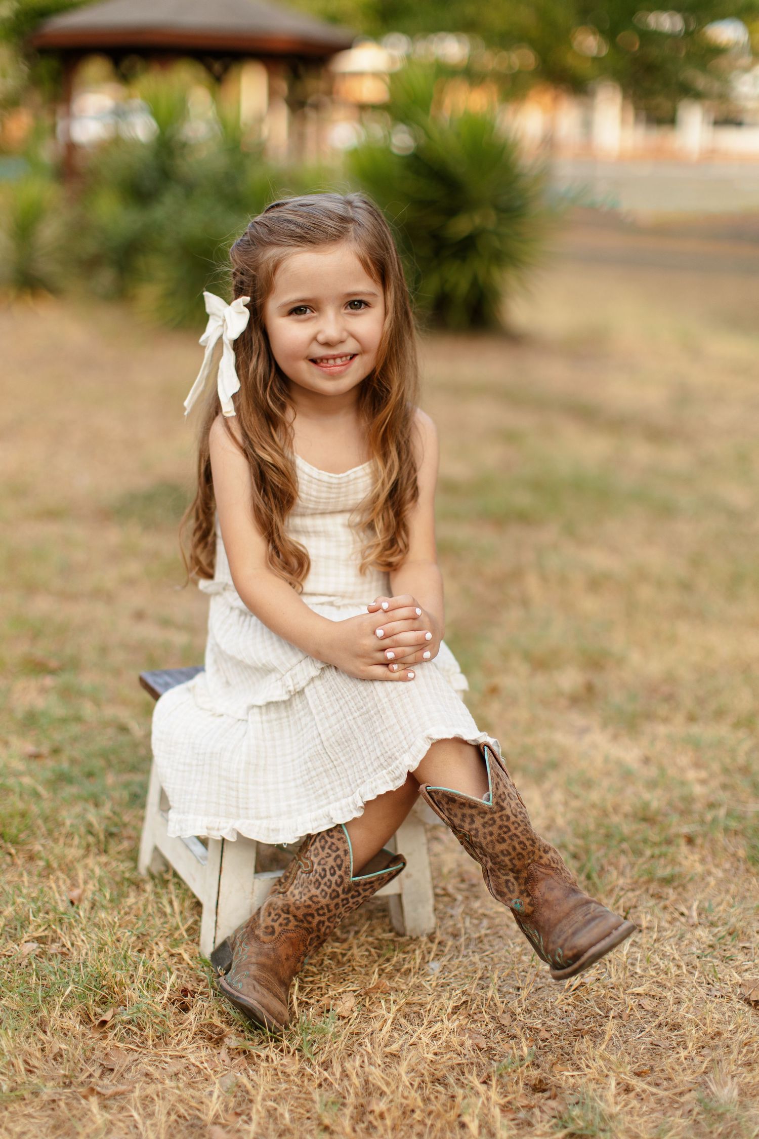 A little girl wearing boots sits on a stool for a portrait  by Emily Joy Photography, now a wedding photographer in Memphis, TN.