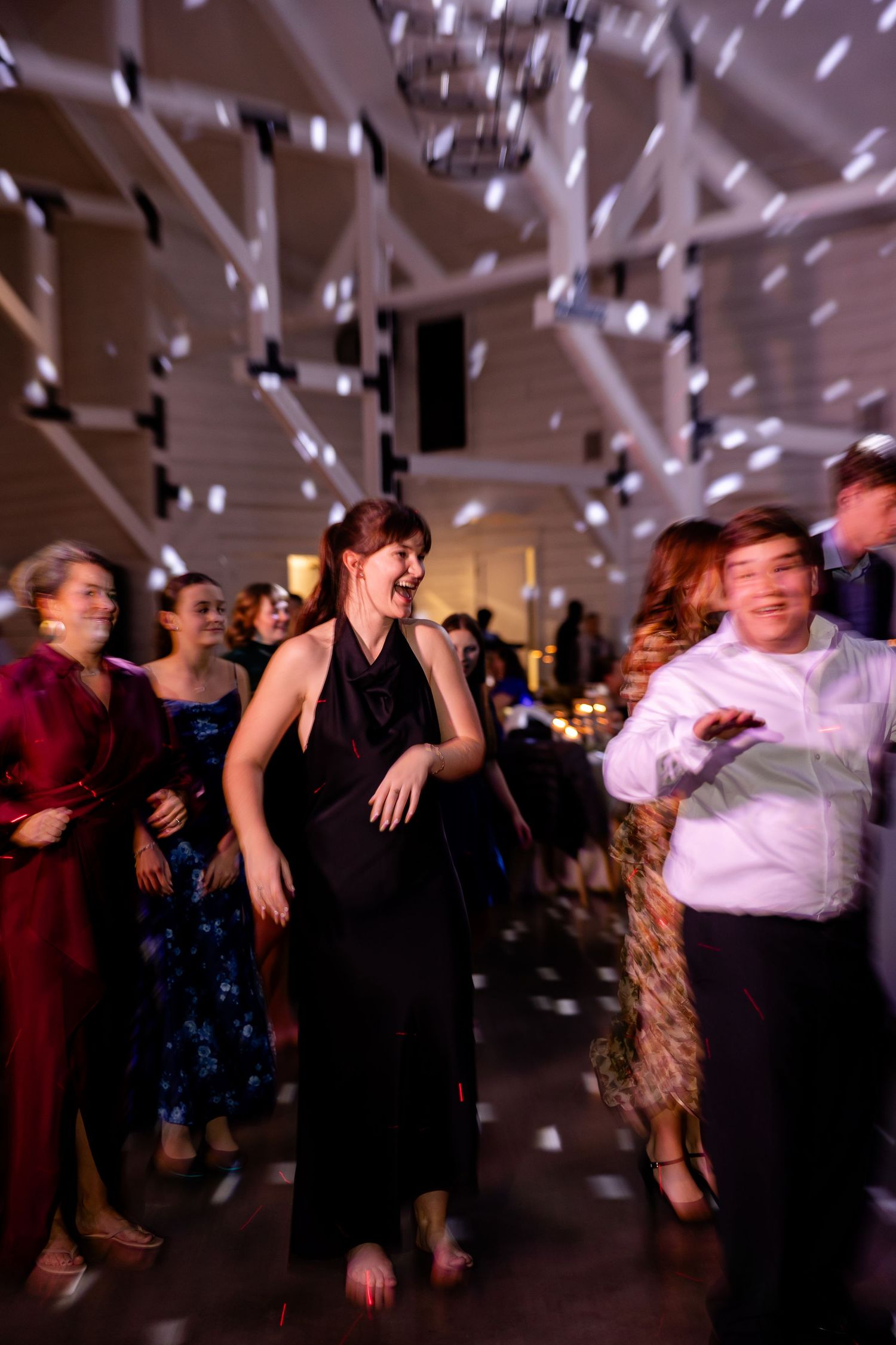 A young lady enjoys party dancing at a reception under disco lights at the Robinshaw wedding venue. Image by Emily Joy, wedding photographer