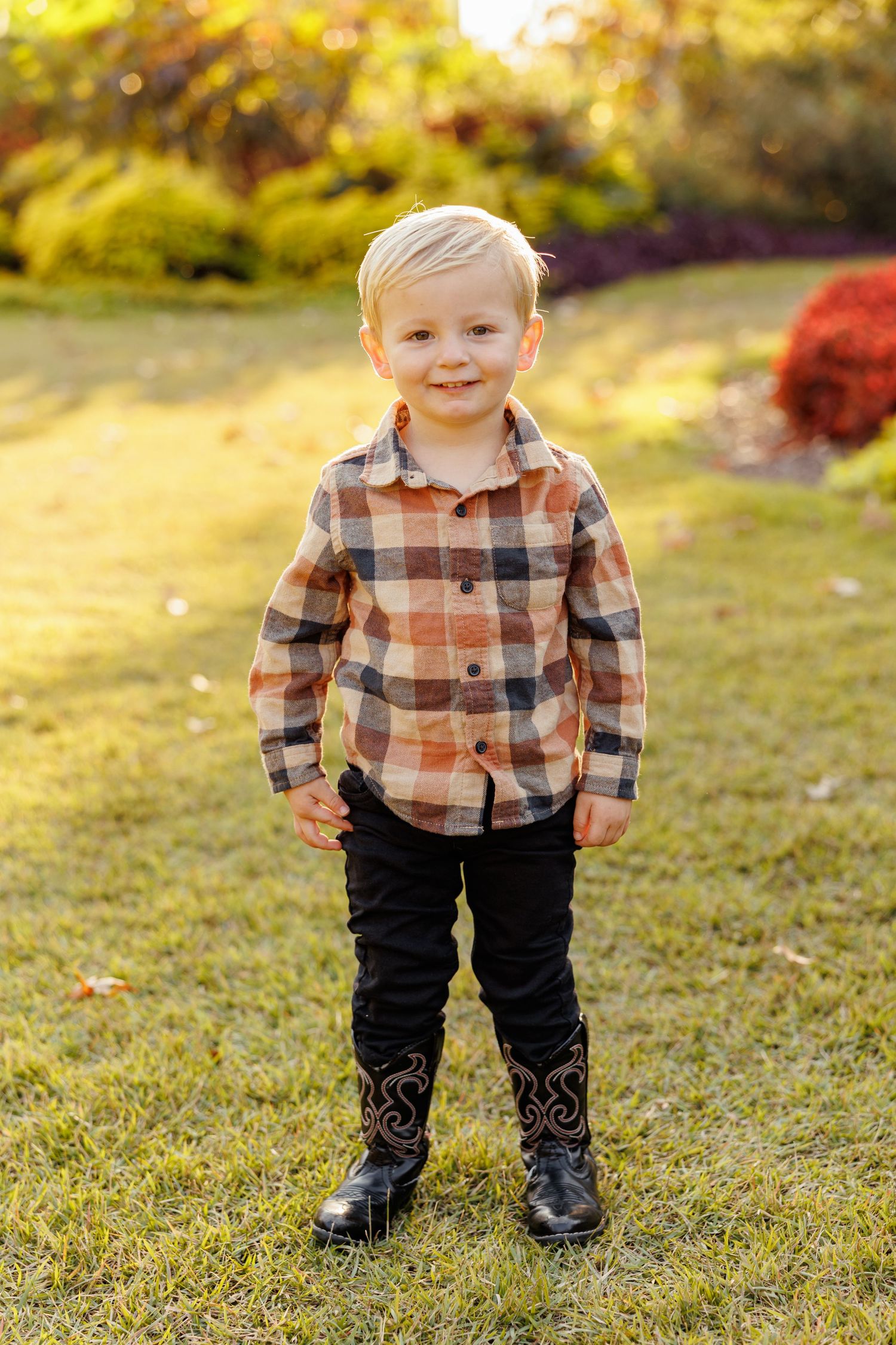Portrait of a toddler in plaid shirt standing in autumn sunshine Portrait of a cheerful little girl by Memphis Family Photographer Emily Joy