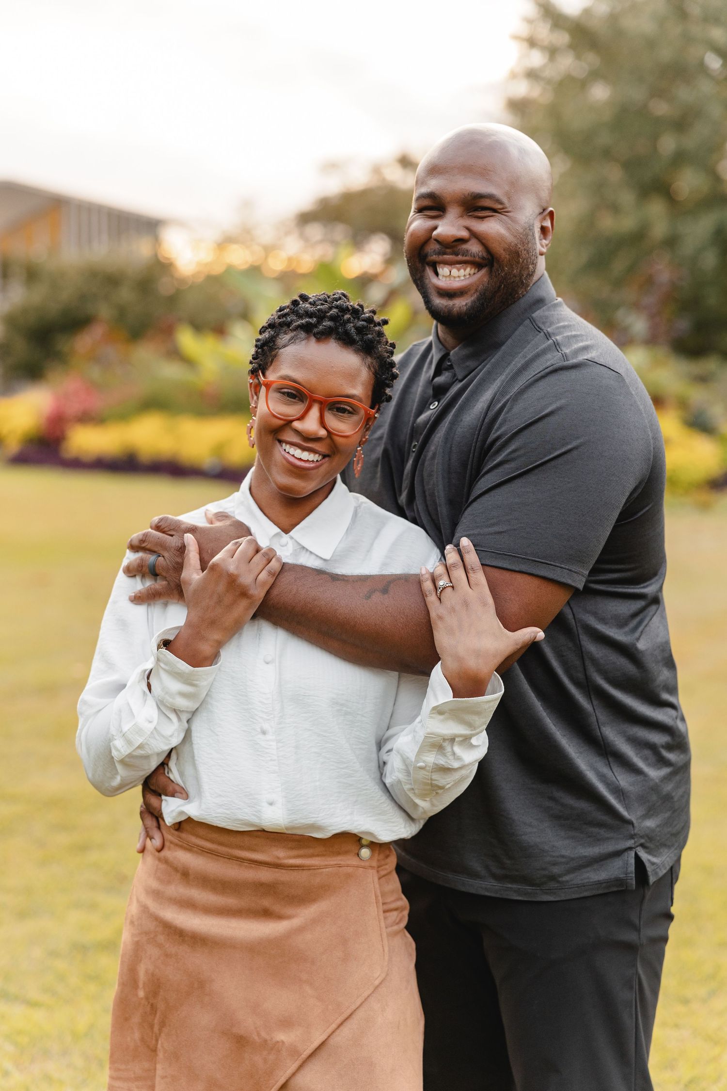 Happy couple embracing and laughing together outdoors in a garden during golden hour by Memphis Family Photographer Emily Joy Photography
