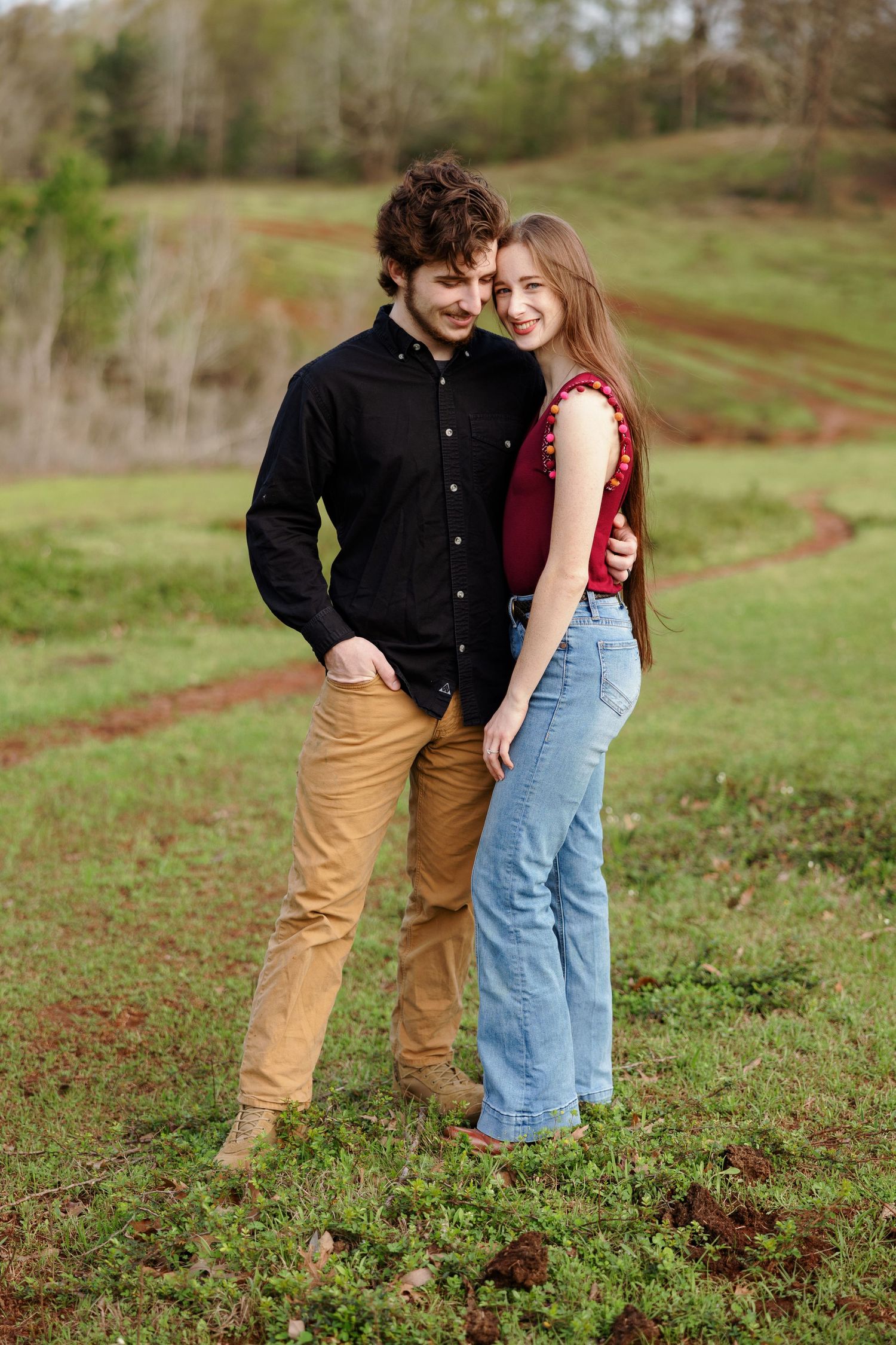 Young engaged couple in a green, hilly pasture for a portrait by Memphis Wedding photographer Emily Joy Photography