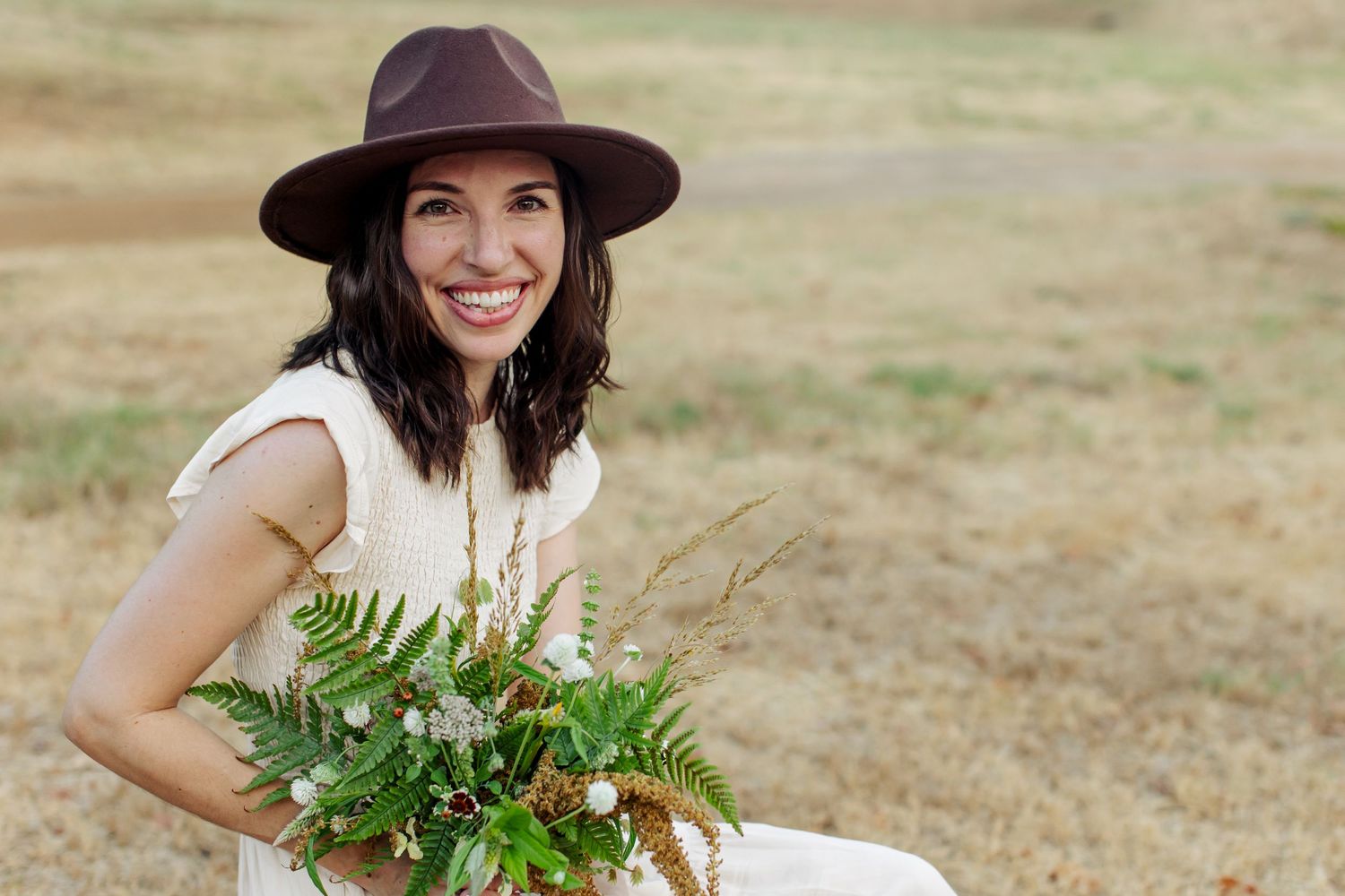 A boho-styled young mother poses with a whimsy bouquet for a portrait  by Emily Joy Photography, now a wedding photographer in Memphis, TN.
