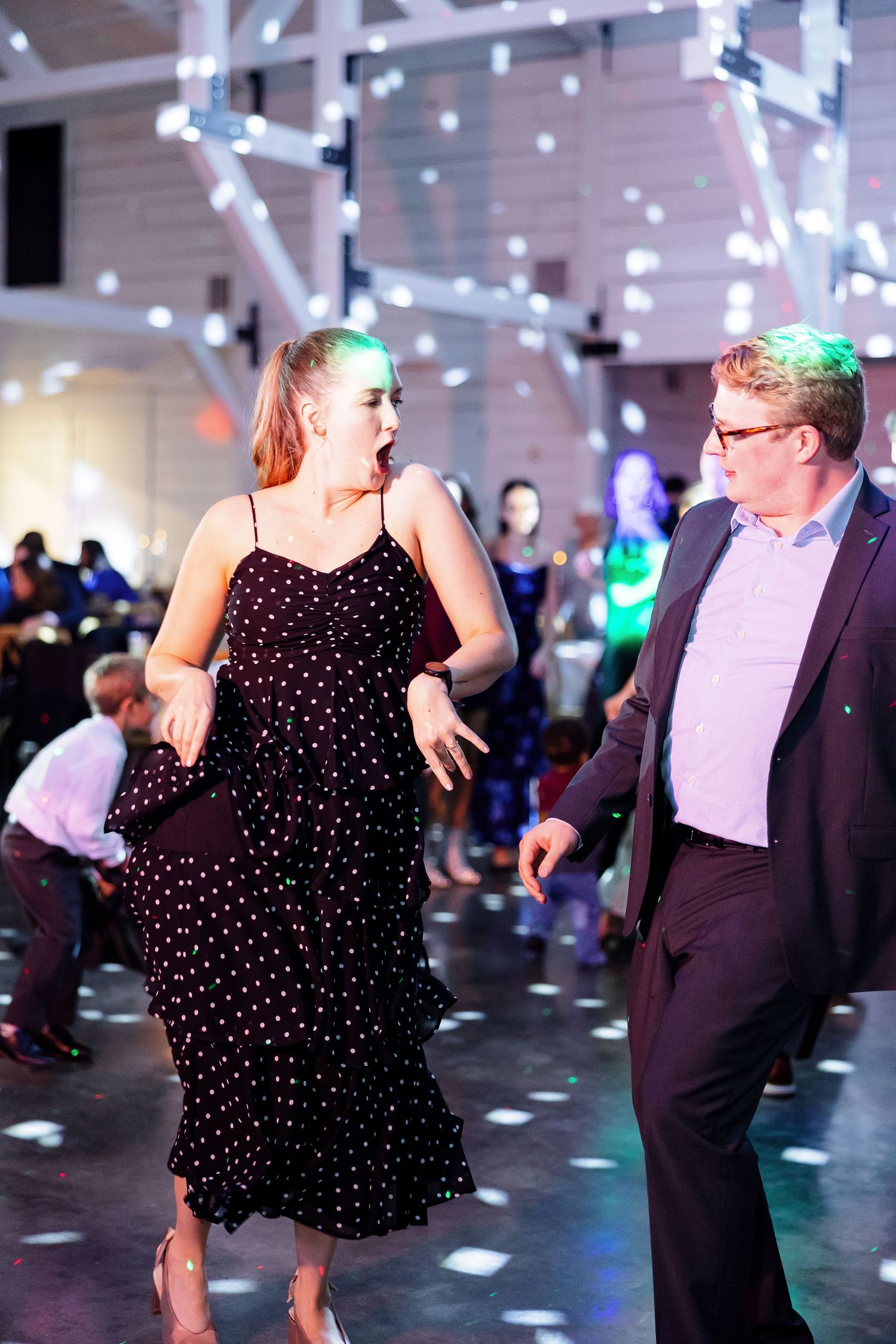 Wedding guests enjoy party dancing with colorful lights and disco ball.  Image by Emily Joy, wedding photographer in Memphis.