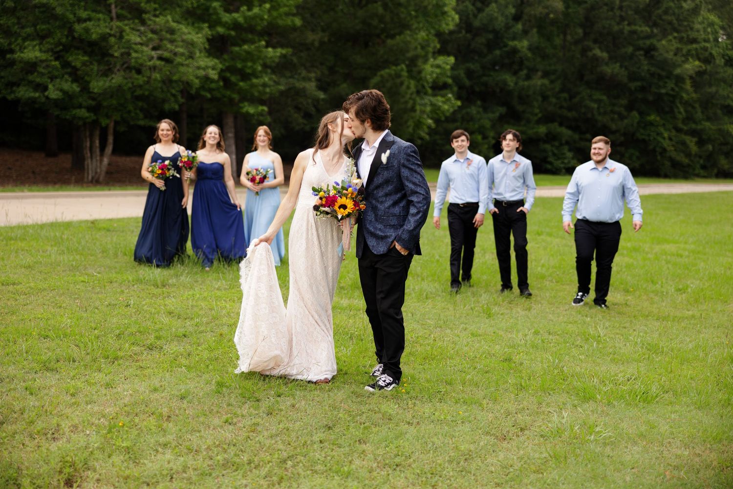 Bridal party smile at bride and groom while they kiss for portrait by Memphis wedding photographer Emily Joy Photography