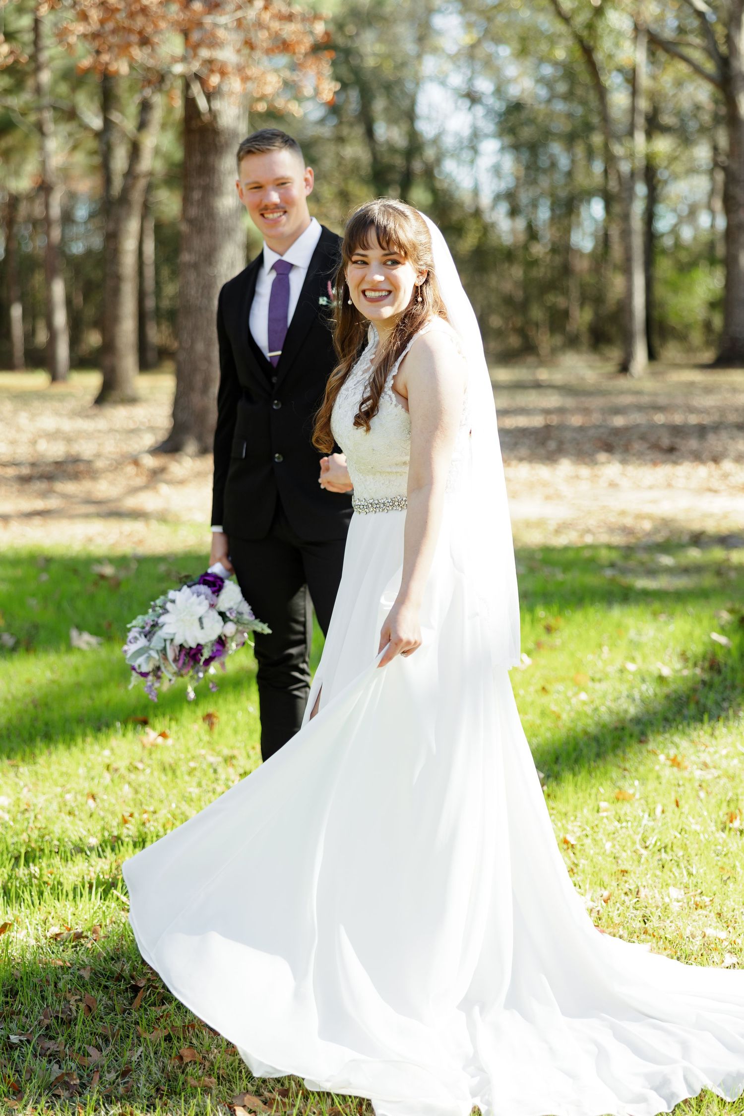 A groom holds his brides hand as she swishes her skirt to-and-fro.