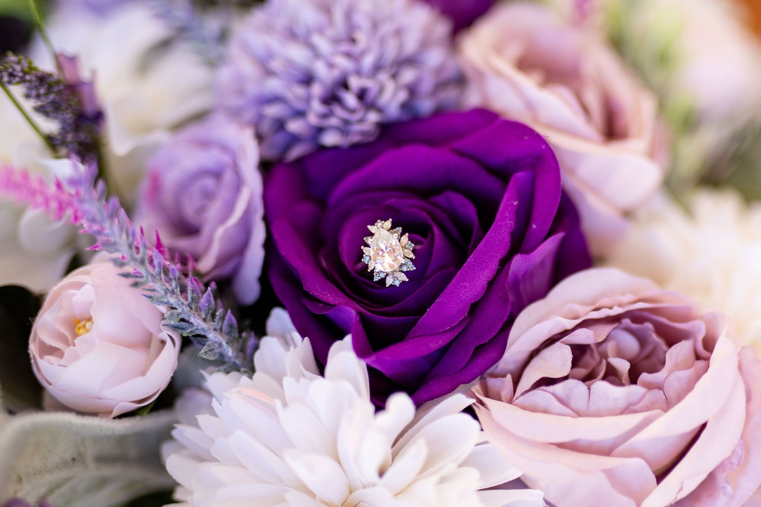 A bride's engagement ring nestled in her purple-themed boquet.