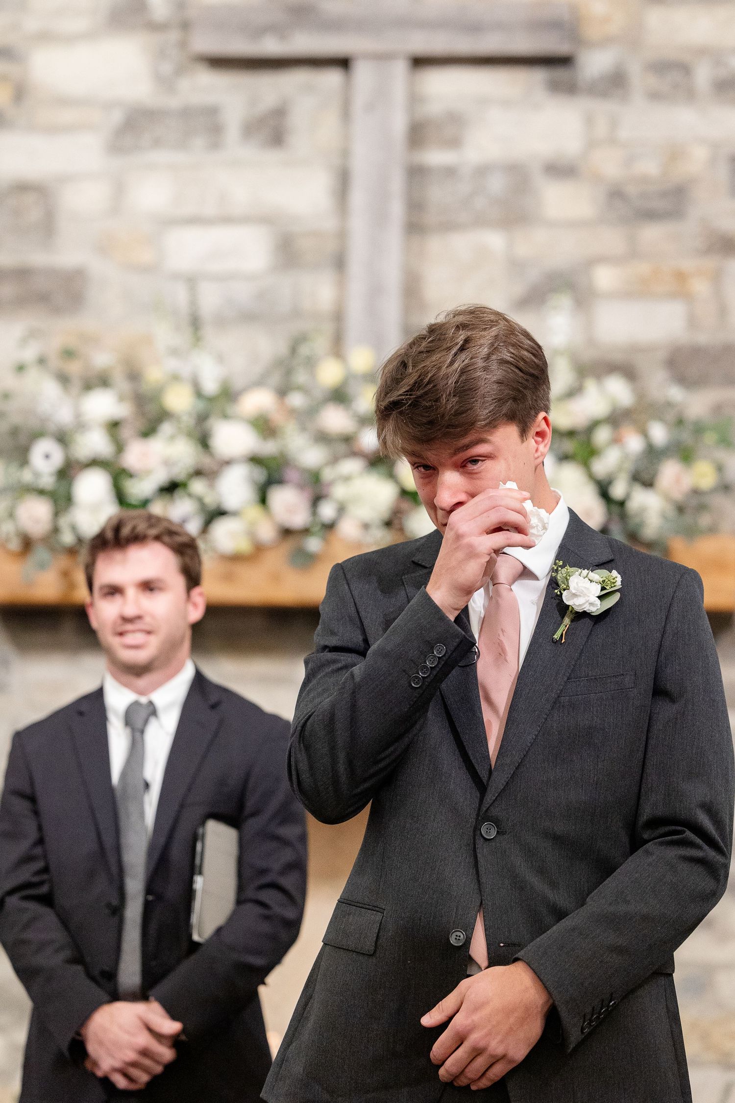 A groom wipes a tear as he watches his bride walk down the aisle toward him. Image by Emily Joy, wedding photographer in Memphis.