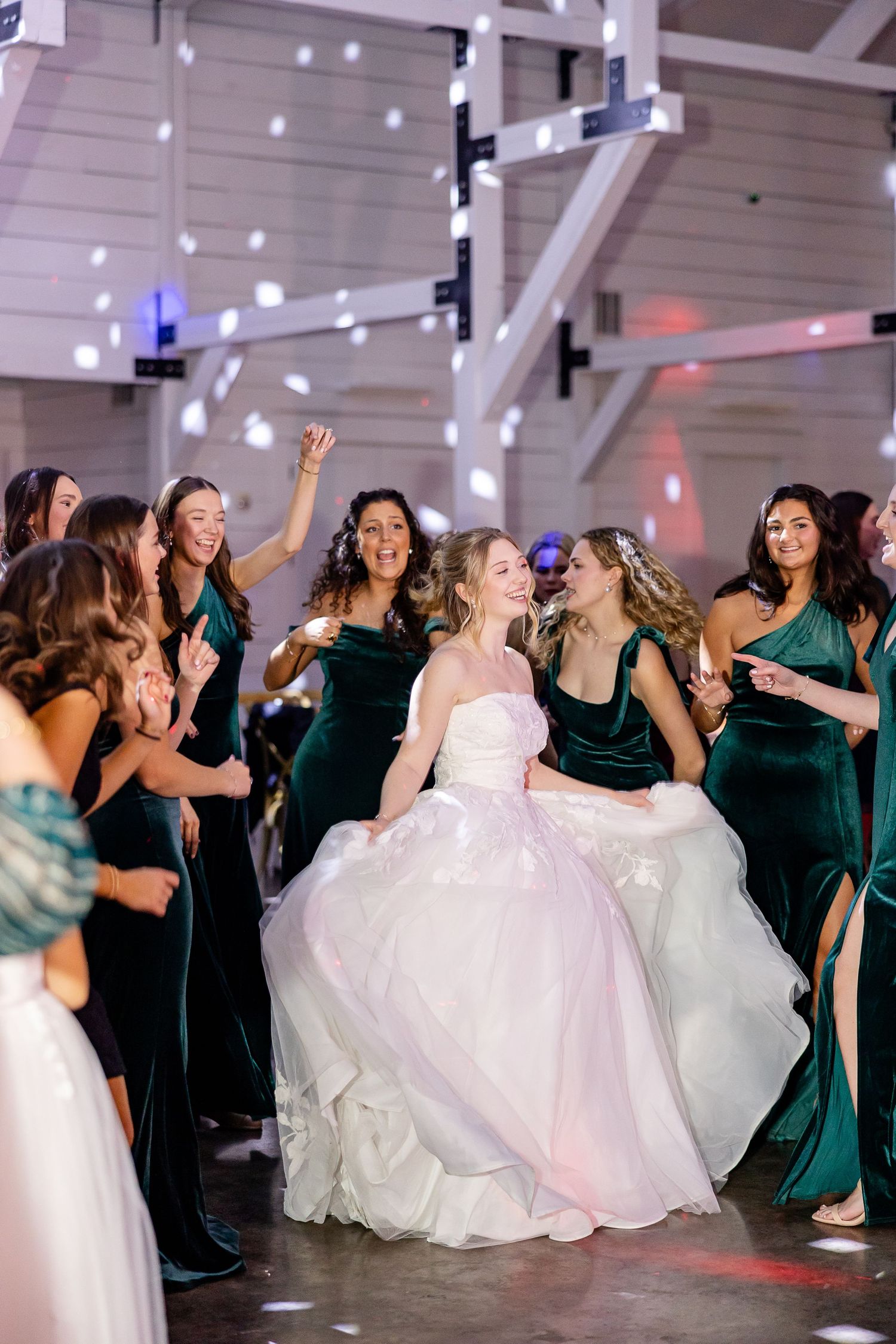 A bride dances in celebration during the reception, surrounded by her bridesmaids. Image by Emily Joy, wedding photographer in Memphis.