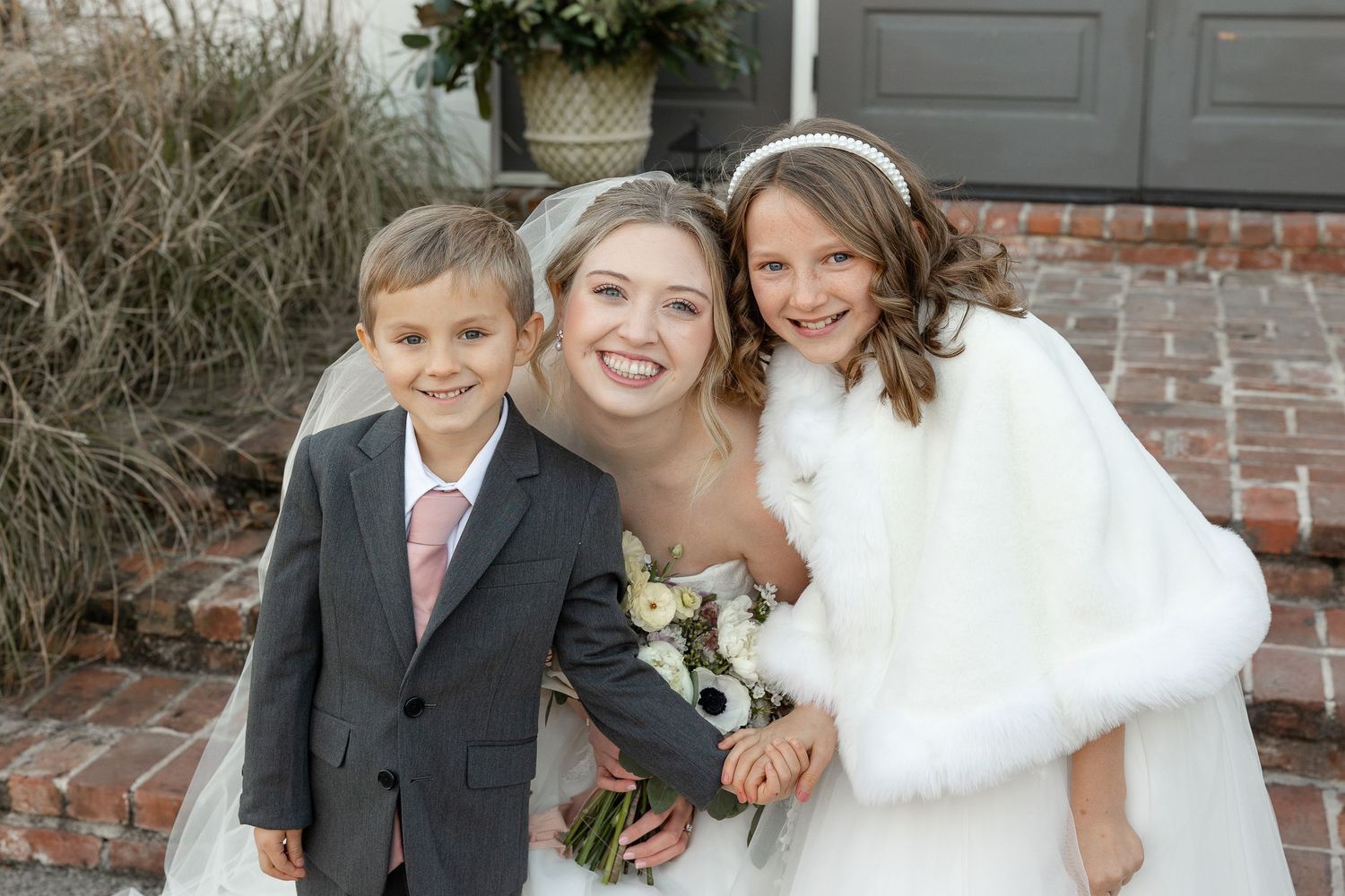 A radiant bride with her flower girl and ring bearer smile for a portrait by Memphis wedding photographer, Emily Joy Photography.