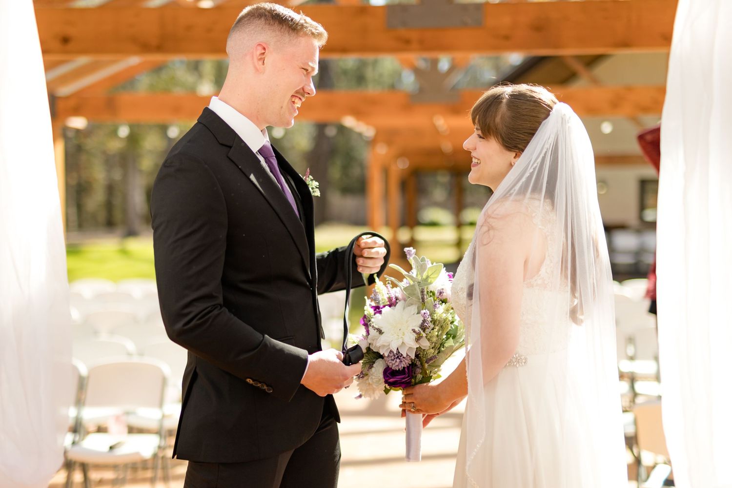 A groom smiles and laughs joyfully as he sees his bride for the first time.