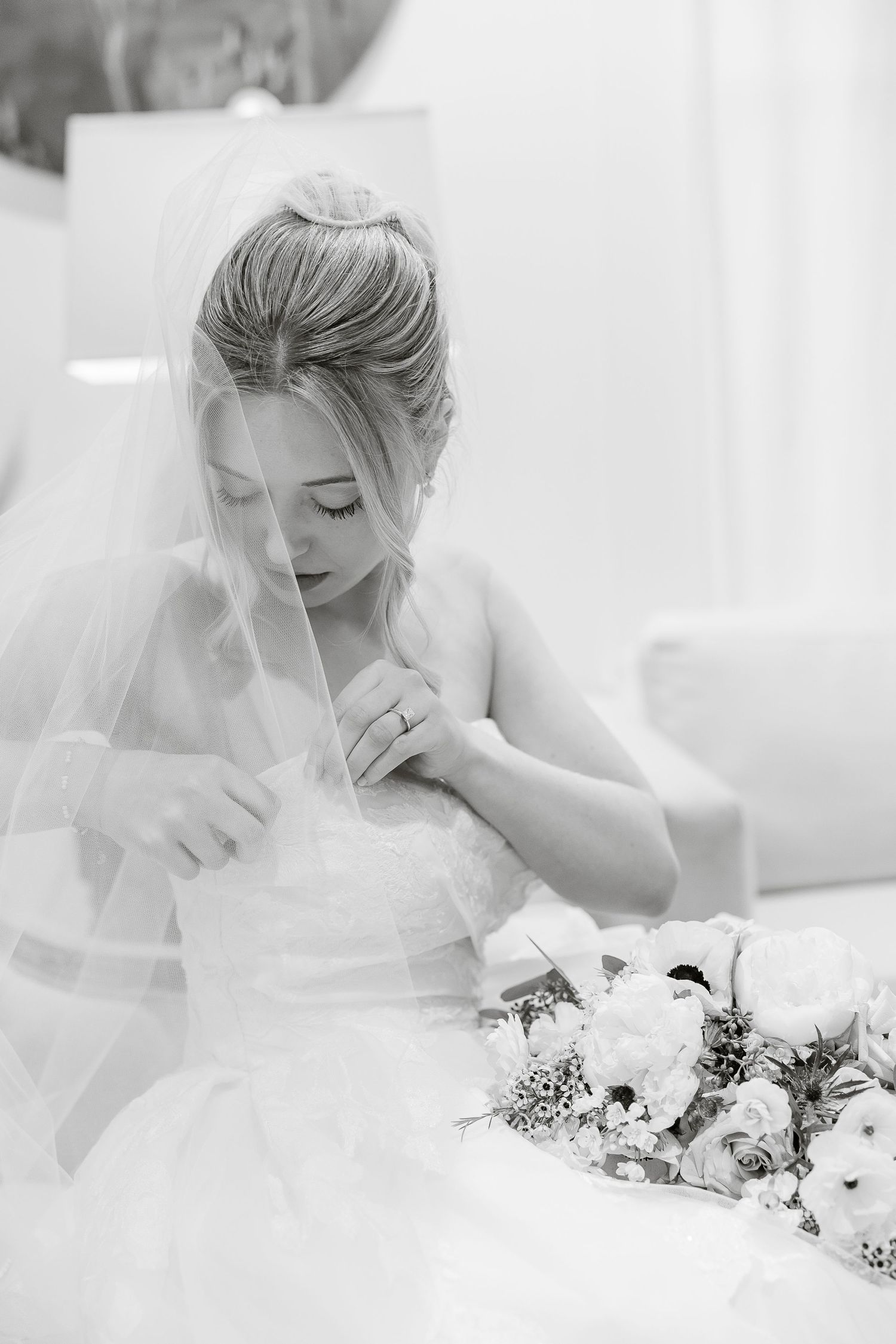 A radiant bride adjusts her dress as her veil partly covers her face. Image by Emily Joy, wedding photographer in Memphis.