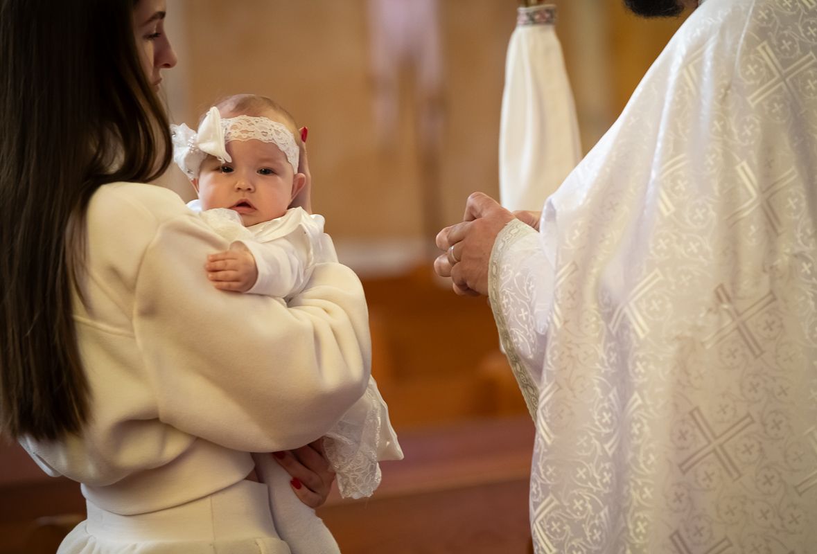 Mother holding her baby during a Toronto church baptism ceremony.