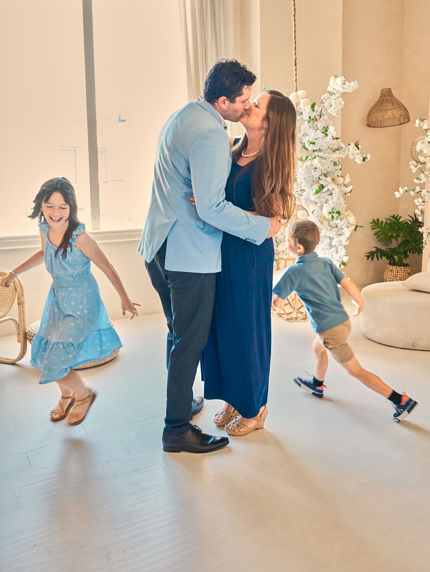 Parents sharing a kiss while their children play around them during a candid Toronto family photography session.
