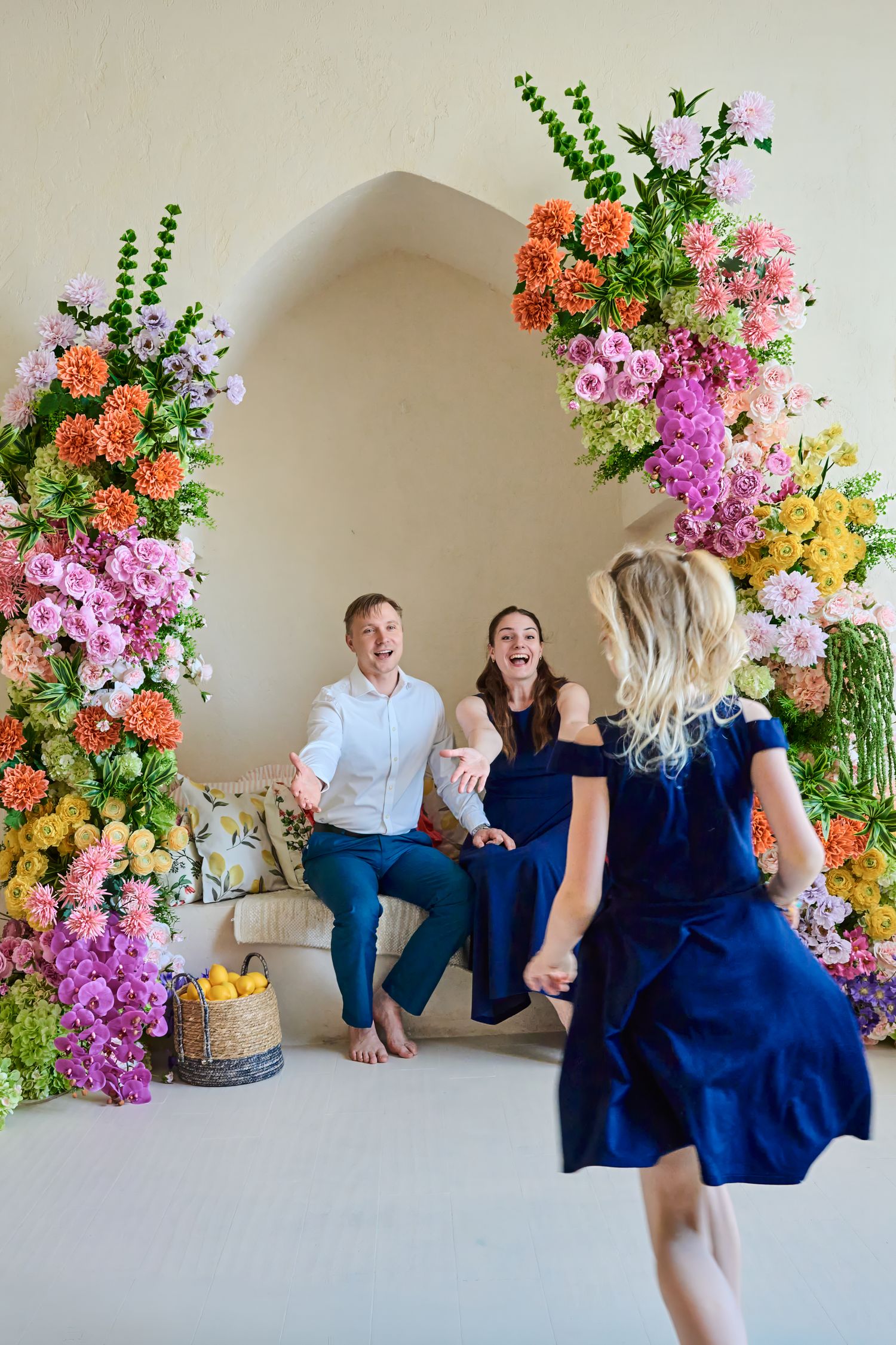 Parents welcoming their daughter during a playful Toronto family photography session in a colourful floral studio.
