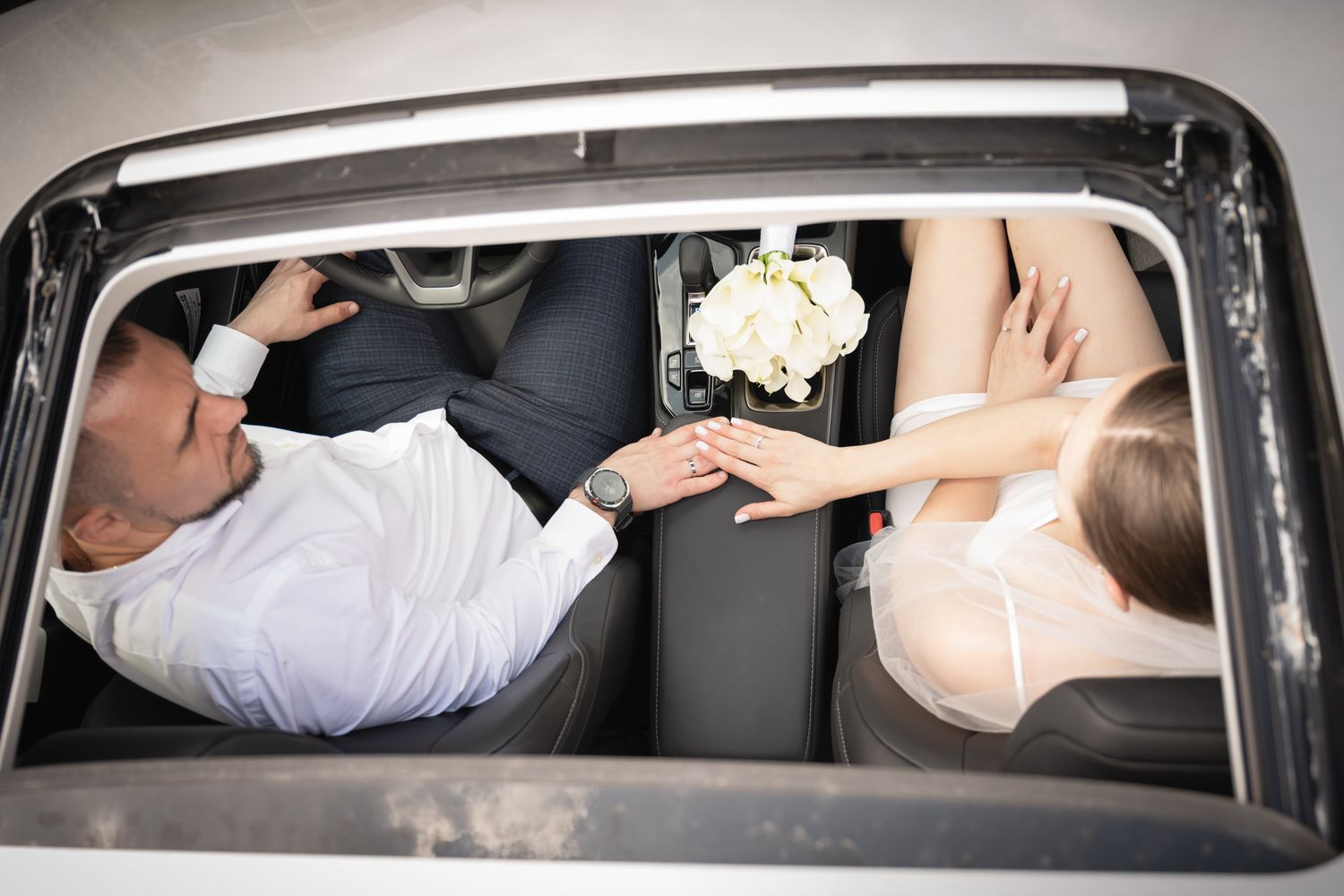 Bride and groom holding hands inside their car during a Toronto wedding photography session.