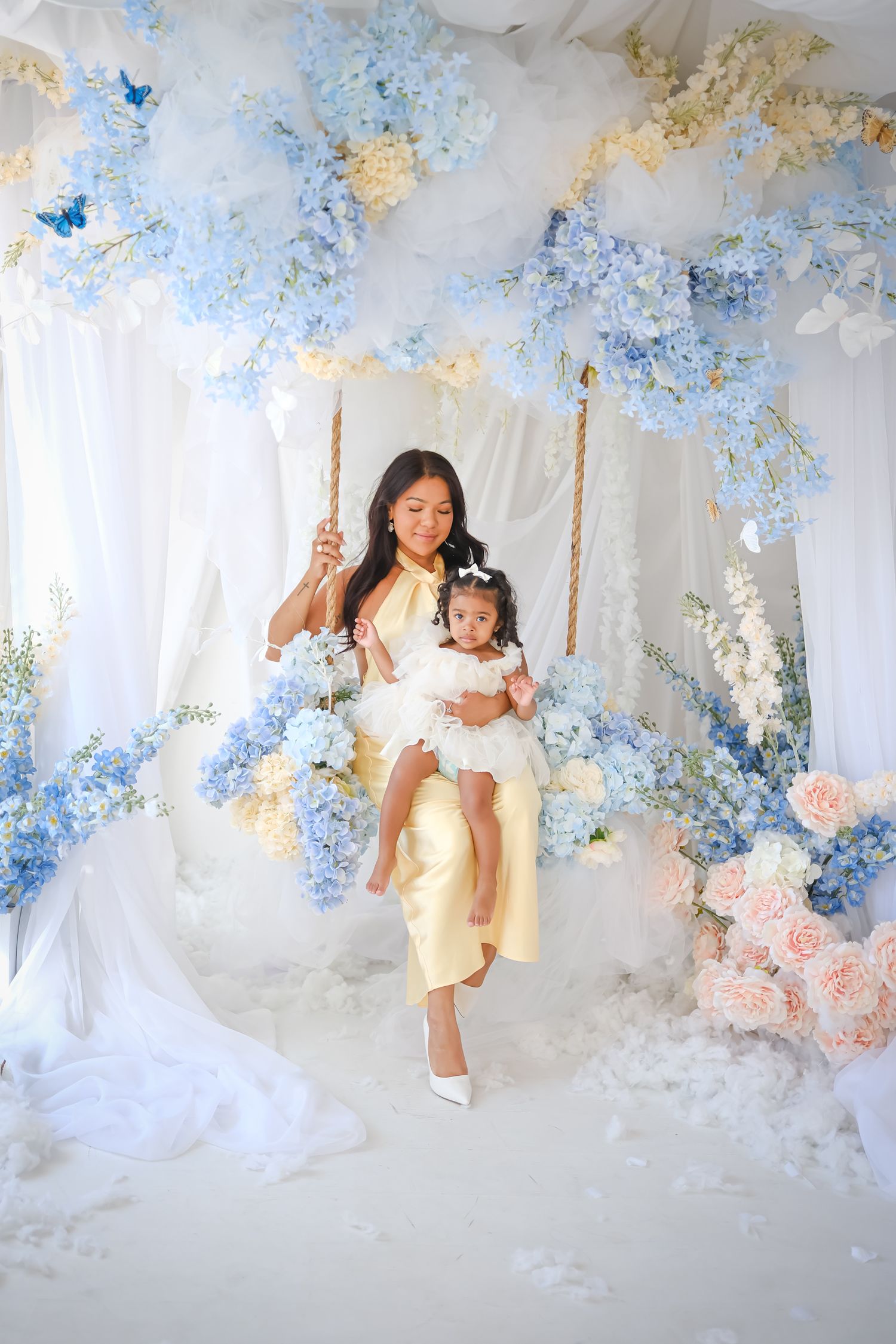 Mother holding her young daughter during a Toronto family photography session in a blue and white floral studio.