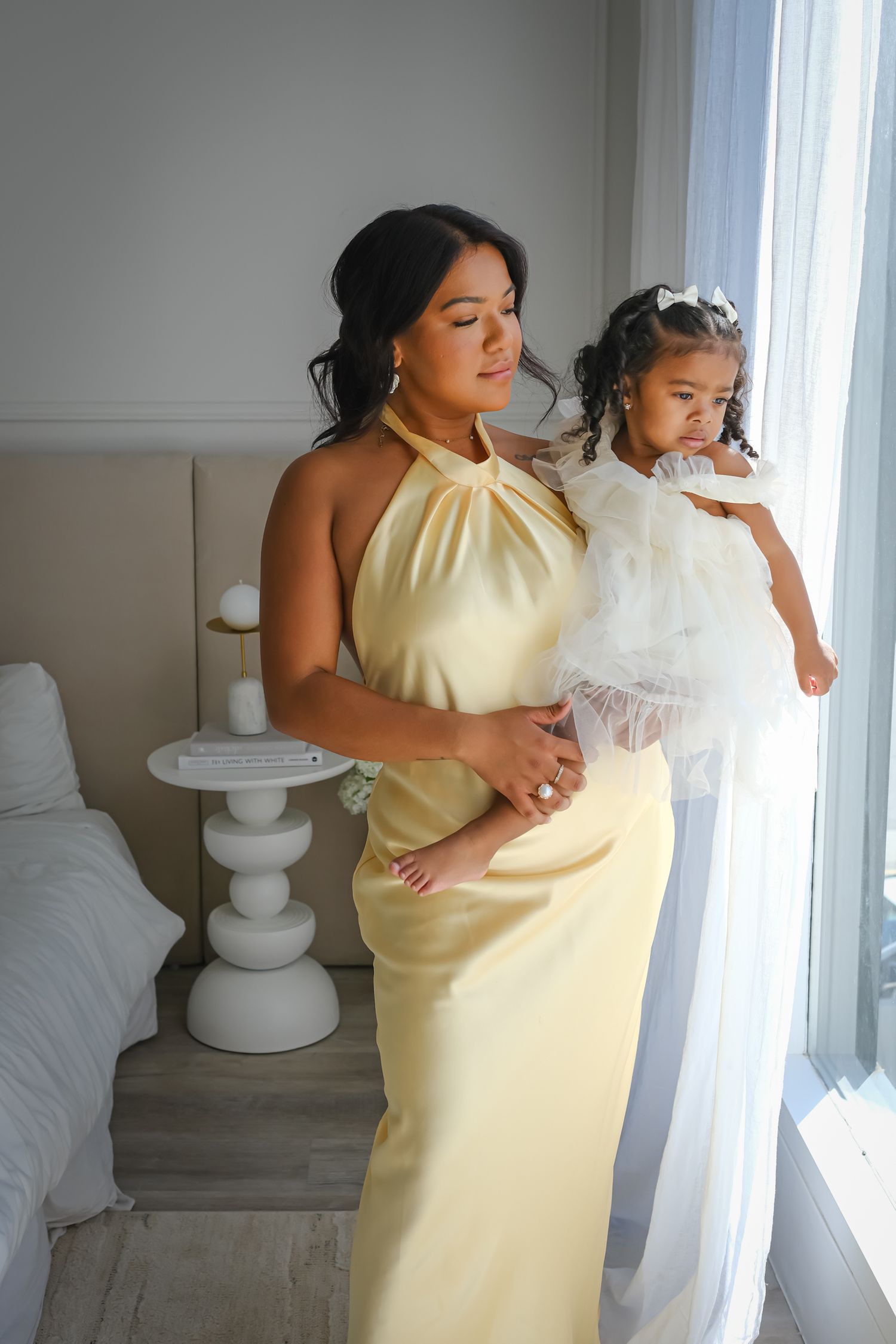 Mother holding her daughter by a window during a natural Toronto motherhood photography session.