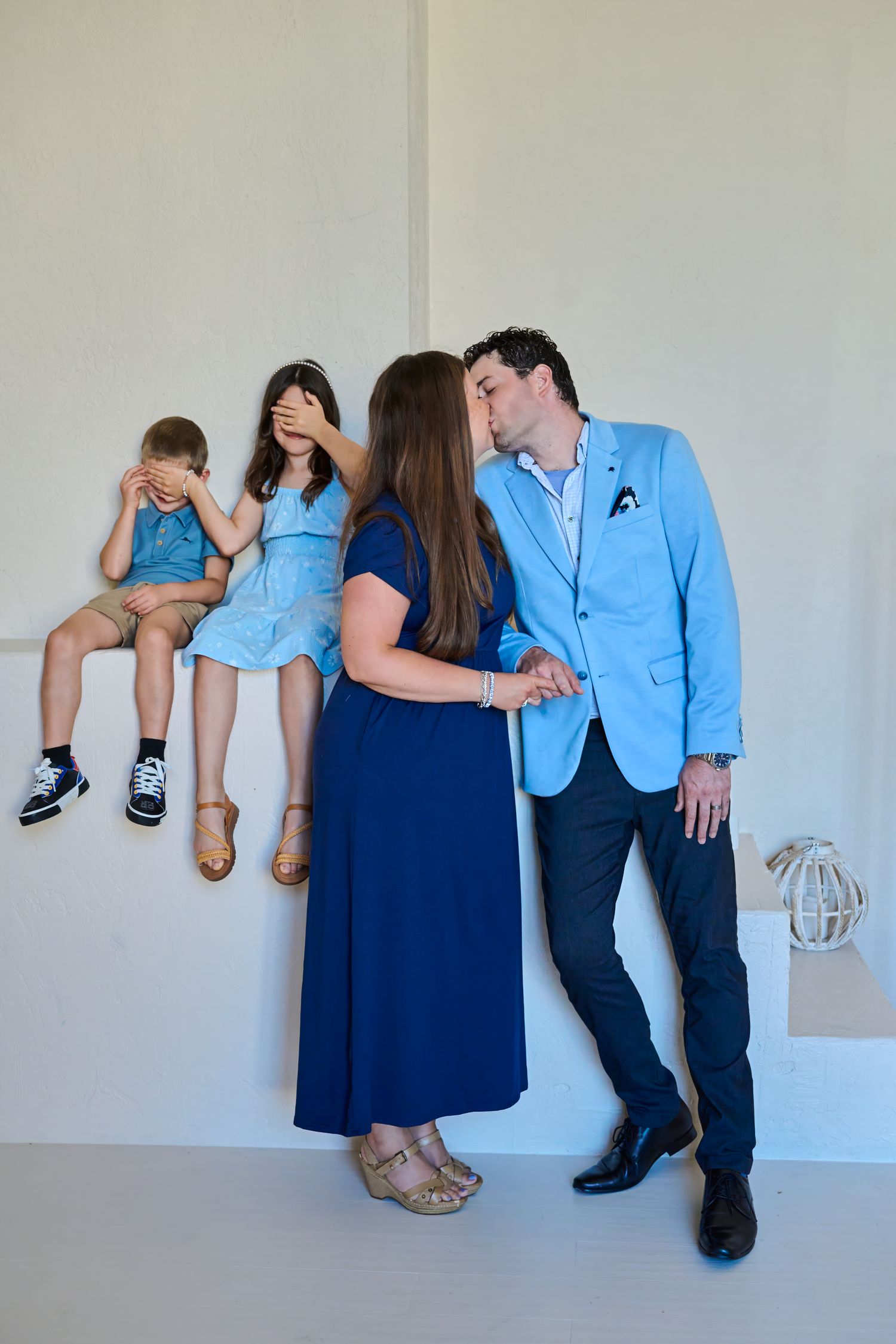 Parents kissing while their children playfully cover their eyes during a candid Toronto family session.