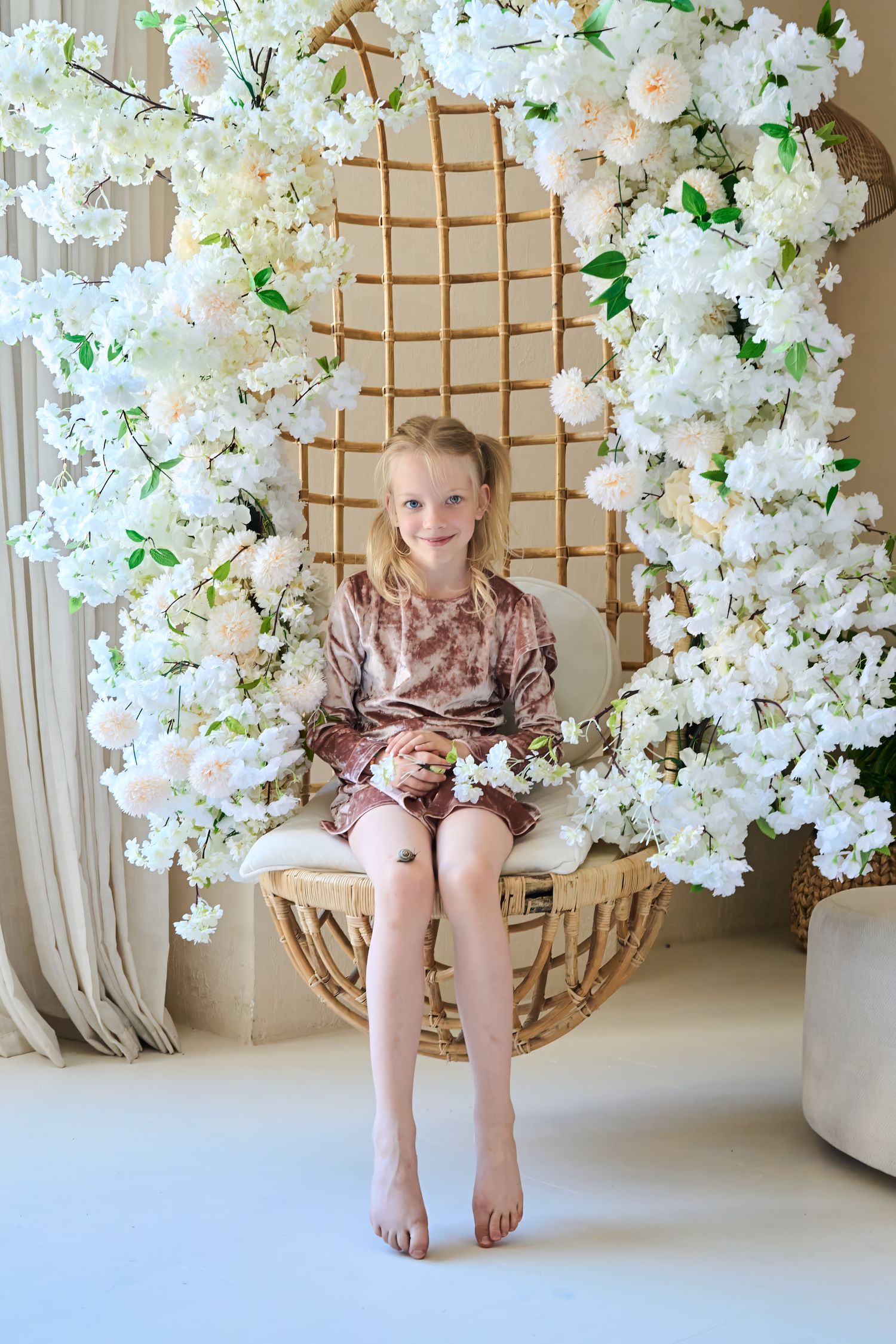 Young girl seated in a white floral swing during a Toronto child and family portrait session.