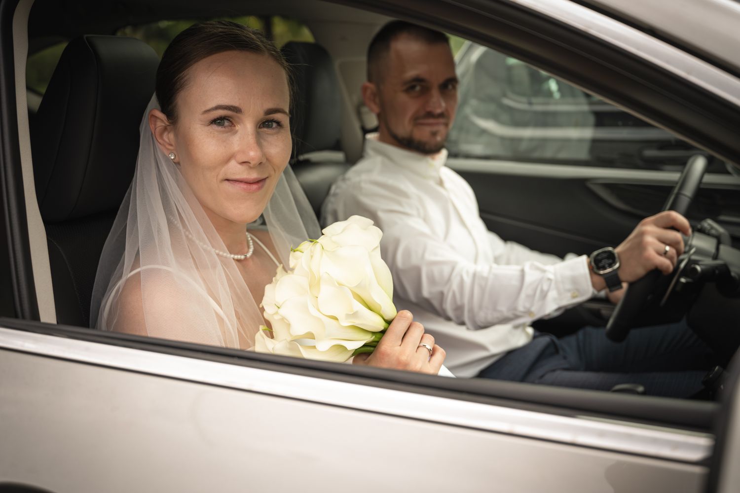 Bride holding her bouquet beside the groom in their car during a Toronto wedding day.