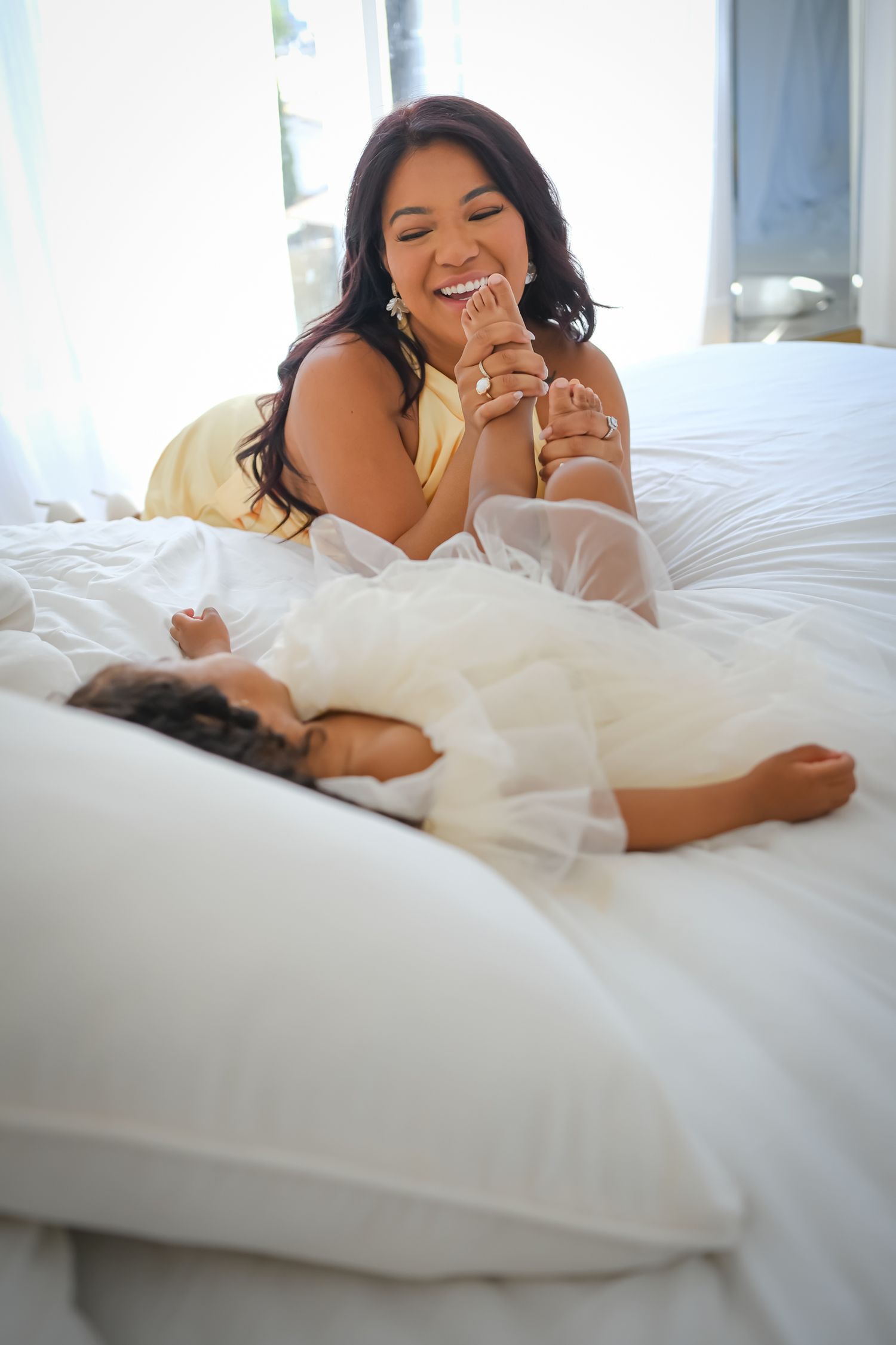 Mother laughing and playing with her daughter during a relaxed Toronto motherhood photography session.