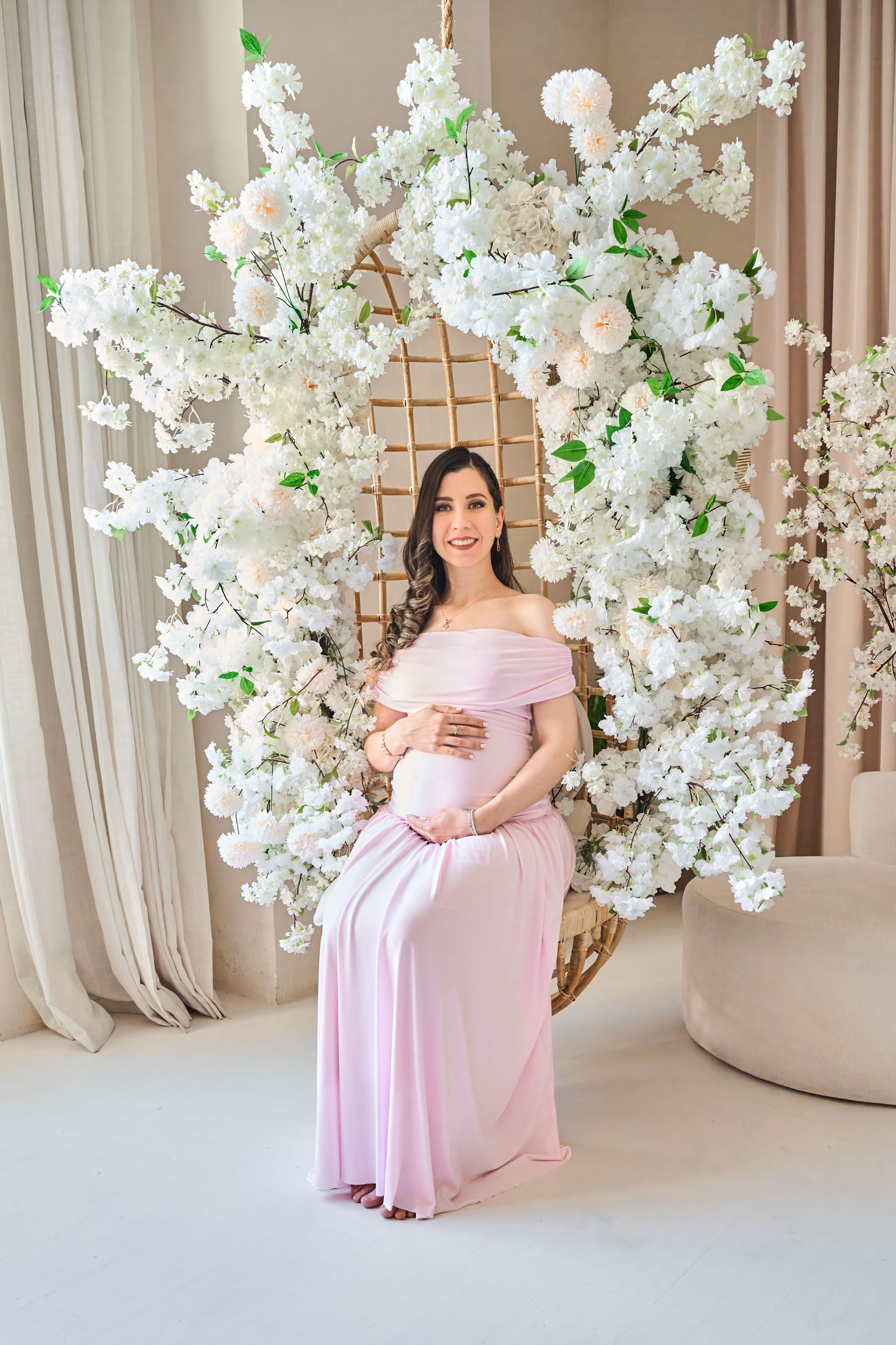 Pregnant woman in a pink dress photographed during a Toronto maternity session in a bright floral studio.