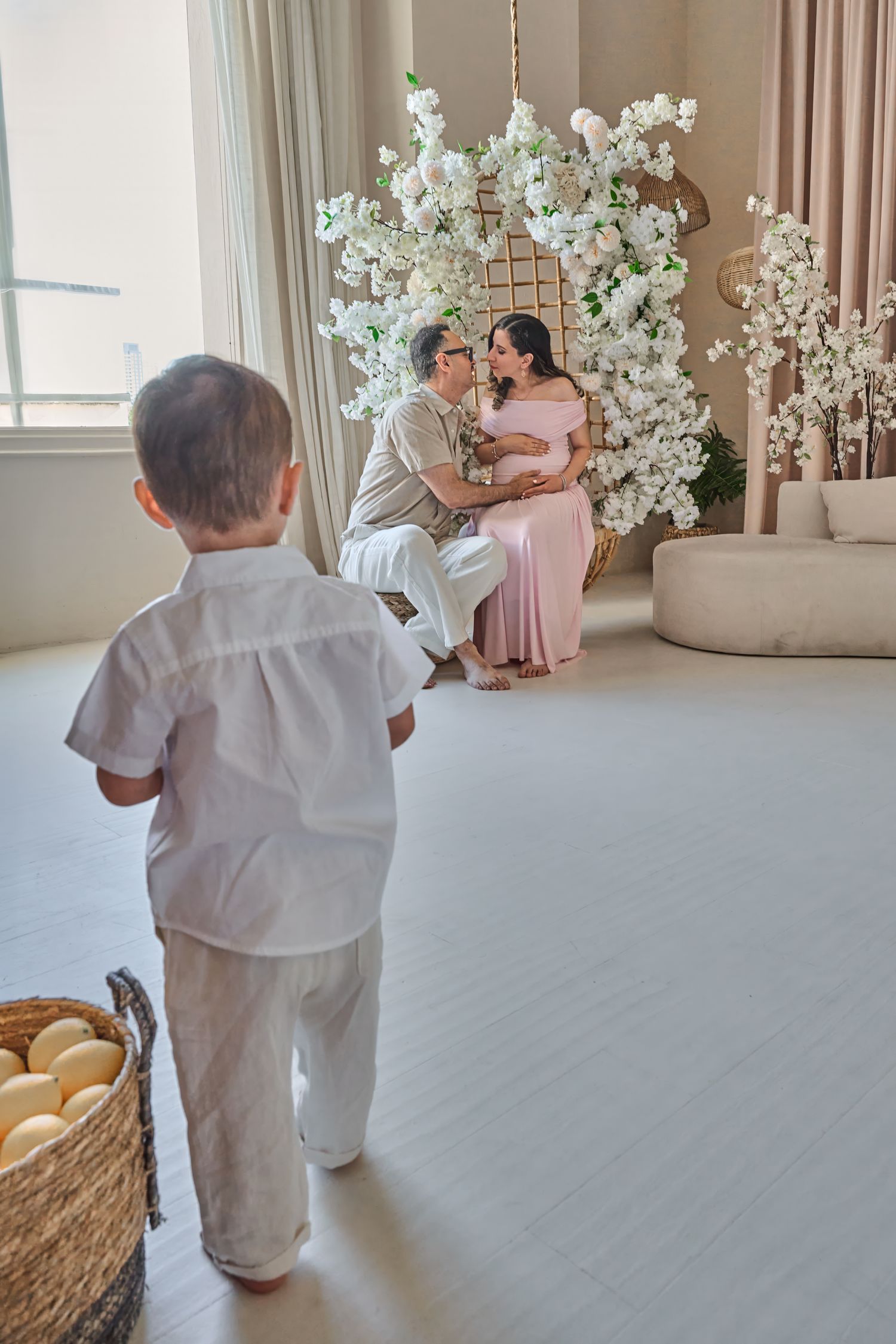 Young child walking toward expecting parents during a Toronto maternity and family photography session.