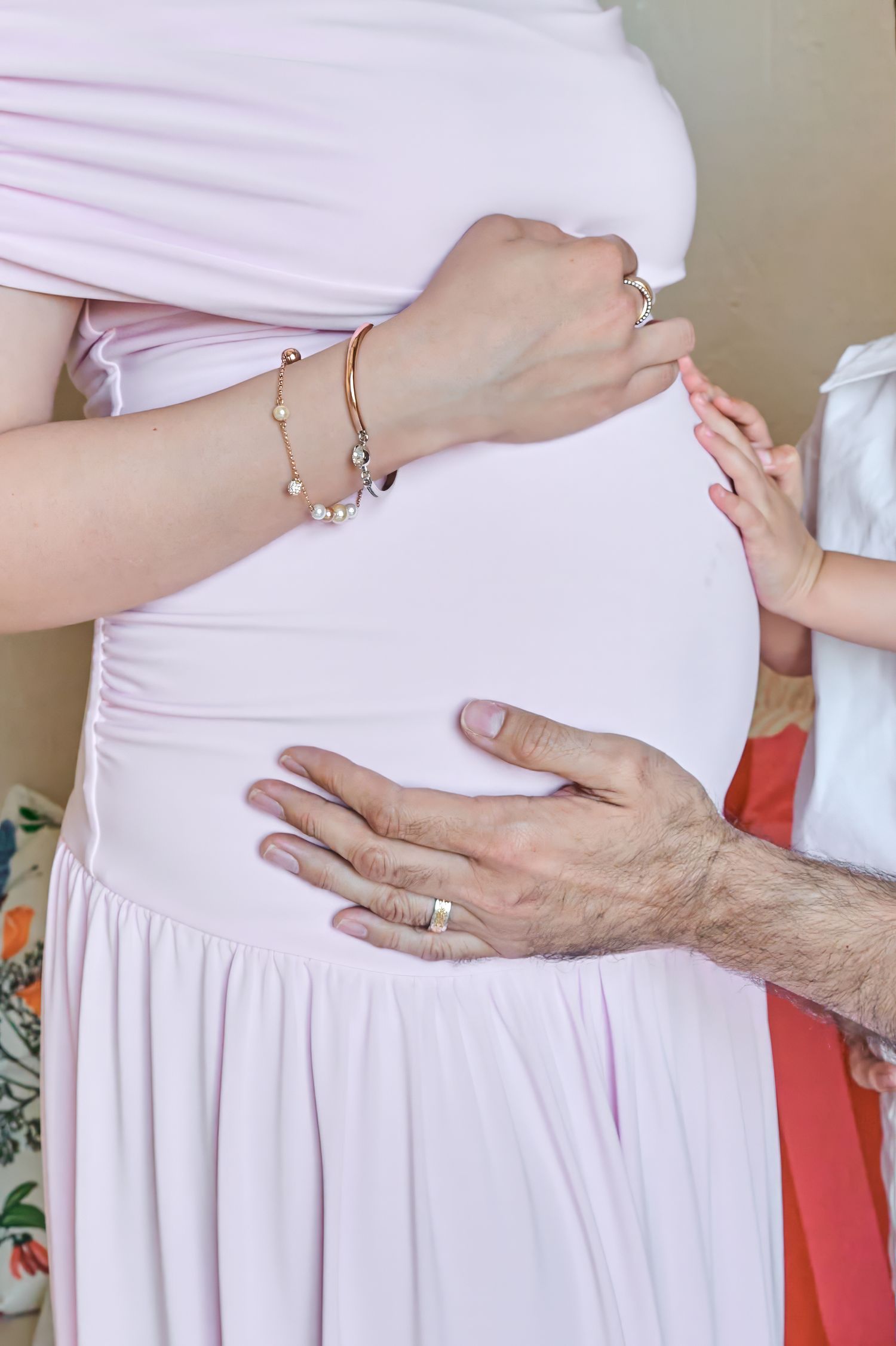 Parents and child placing their hands on a pregnant belly during a Toronto maternity photography session.