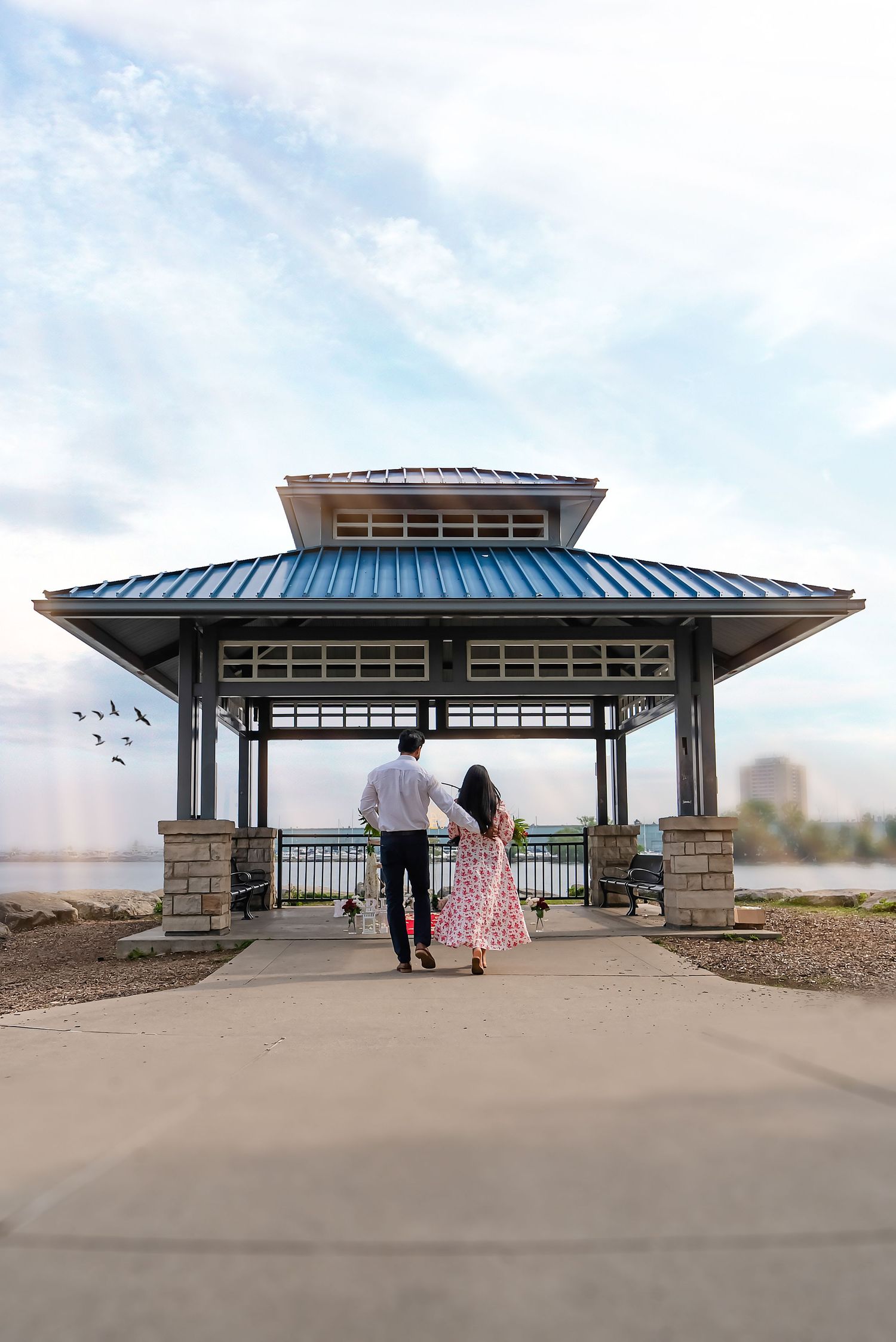 Couple walking toward a waterfront proposal setup during a Toronto engagement photography session.