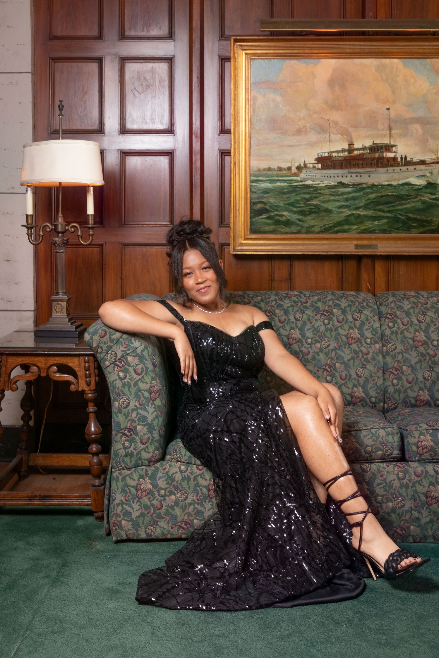 A glamorous photoshoot featuring a sparkly black evening gown on a green carpeted floor.