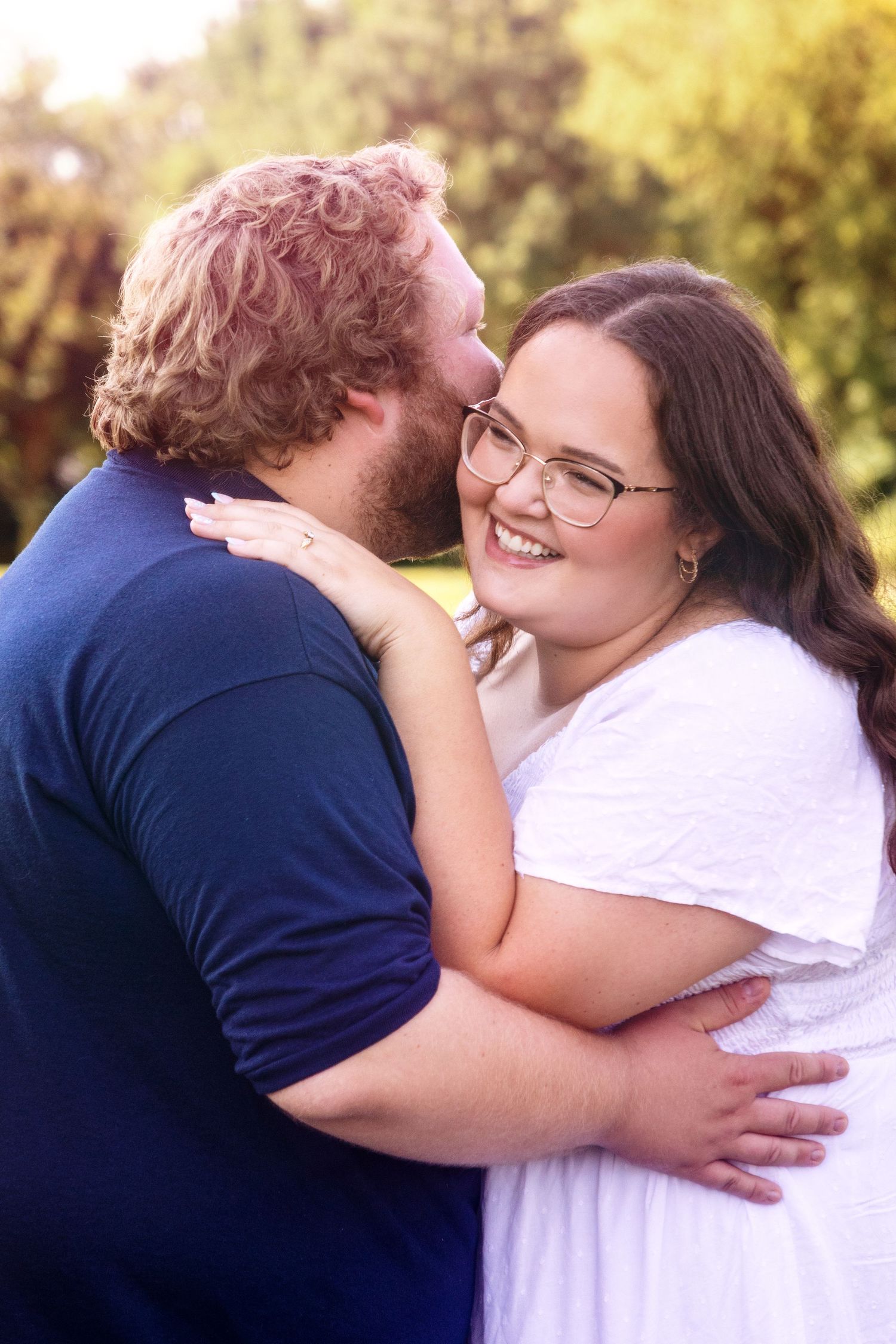 Couple shares tender embraces and laughter in a sunny outdoor setting.