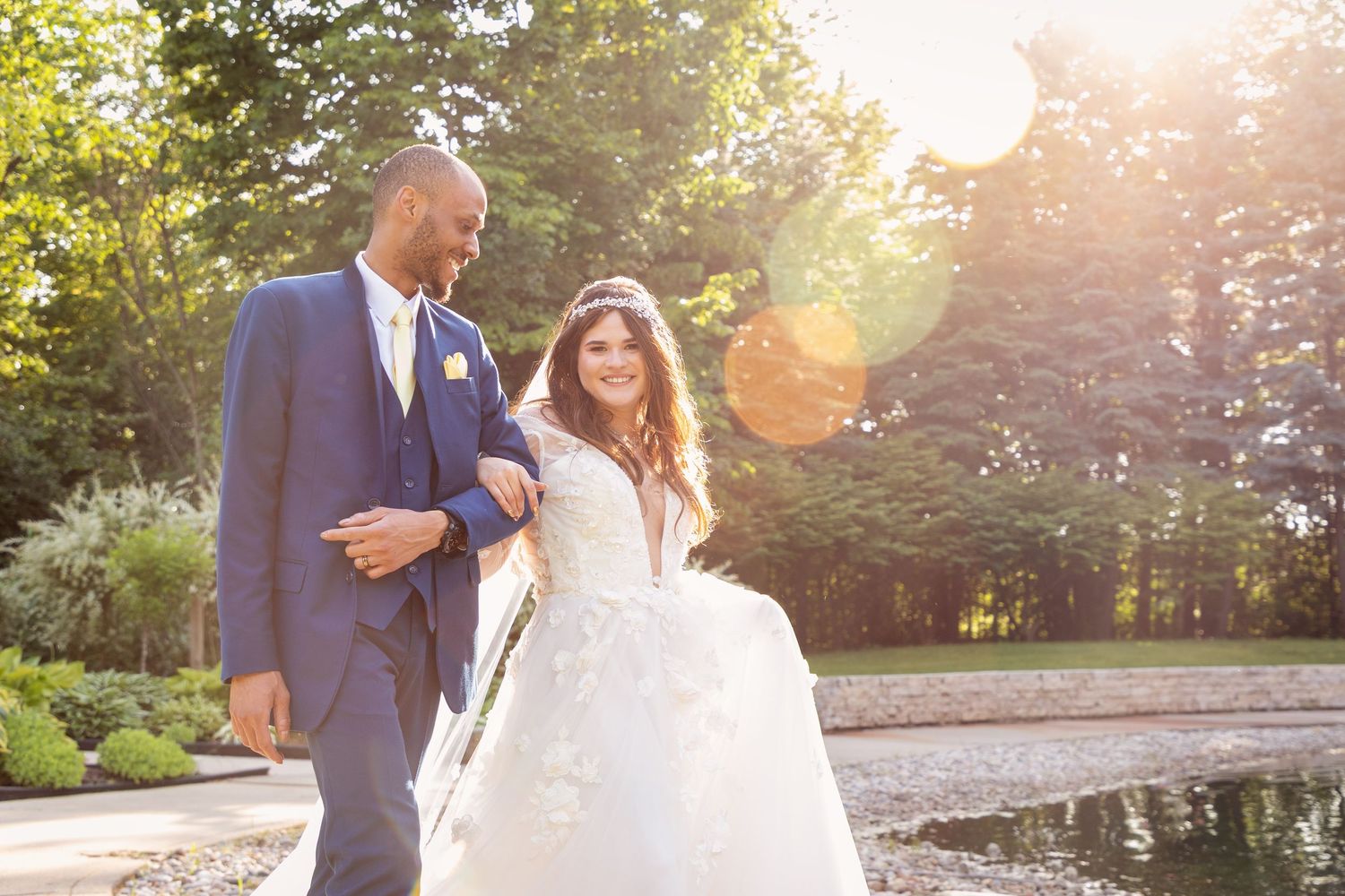Wedding couple dancing outdoors with golden sunlight filtering through trees.