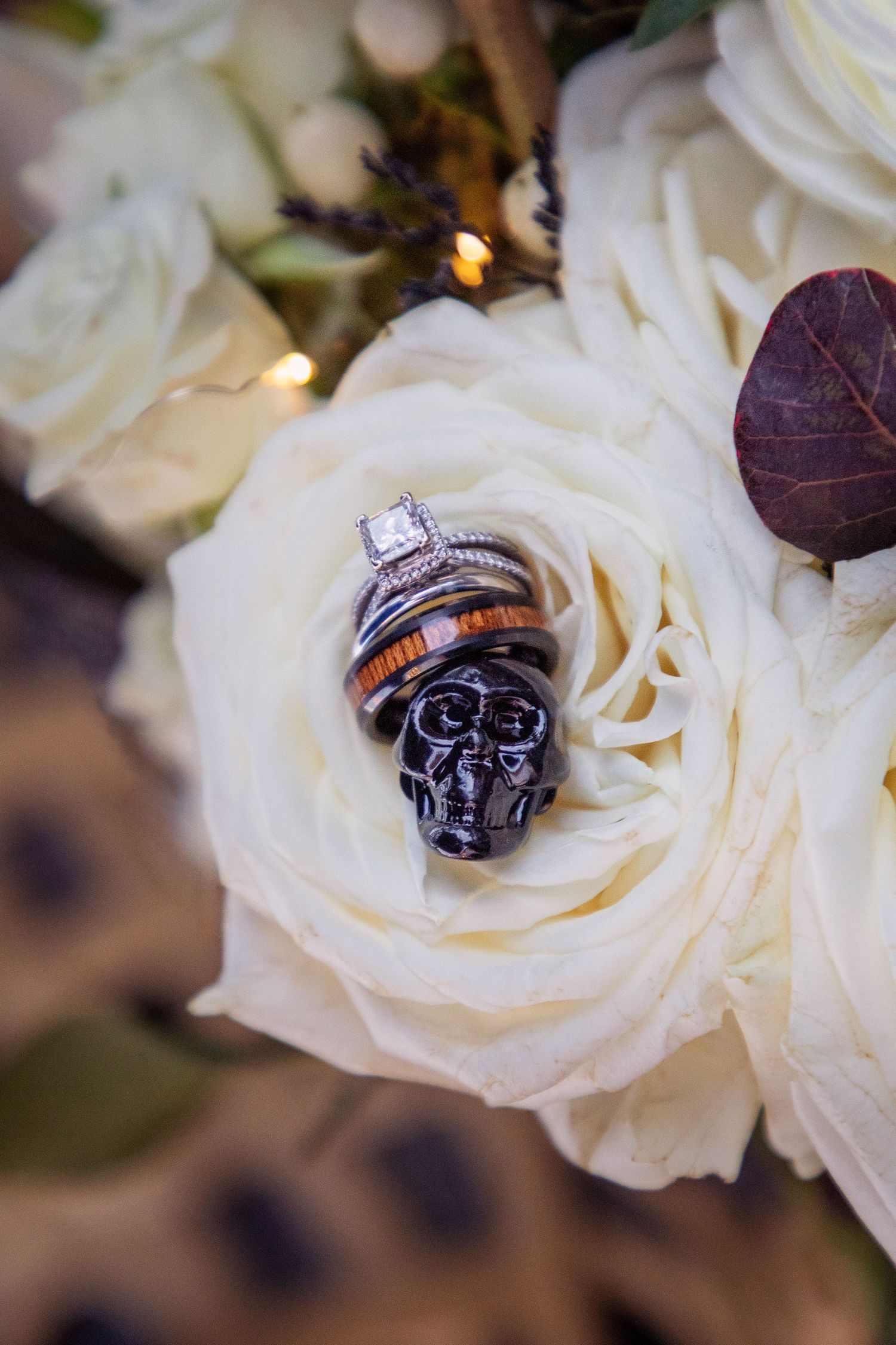 Wedding rings nestled in delicate white rose petals with soft lighting.
