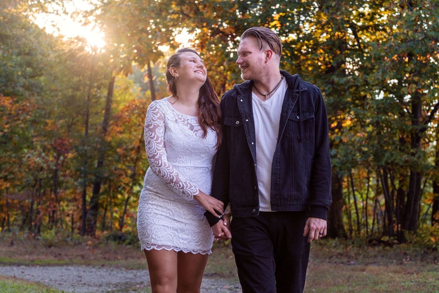A couple poses together in a romantic sunset photoshoot among fall trees.