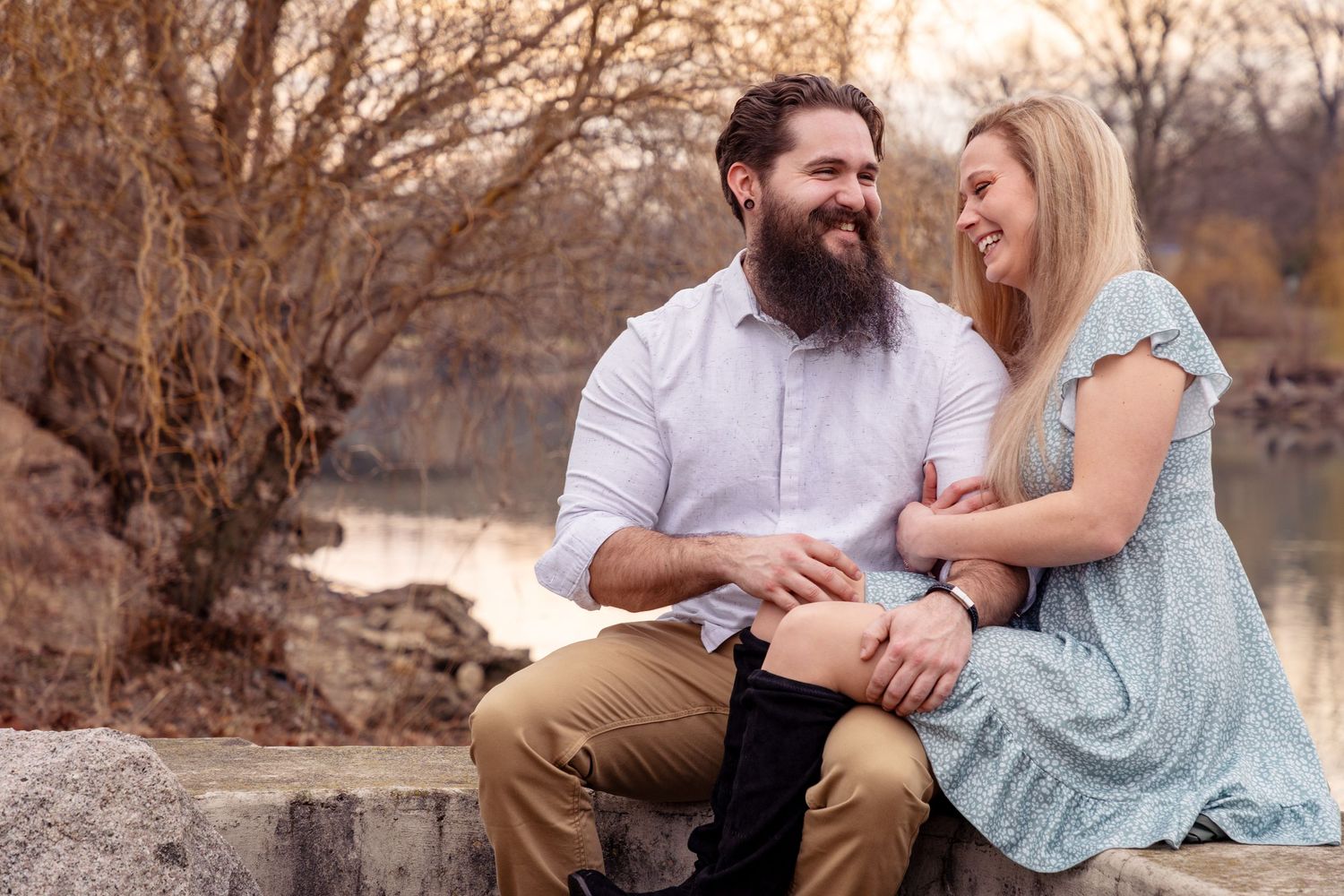 Couple sits close together on rustic bench during autumn sunset.