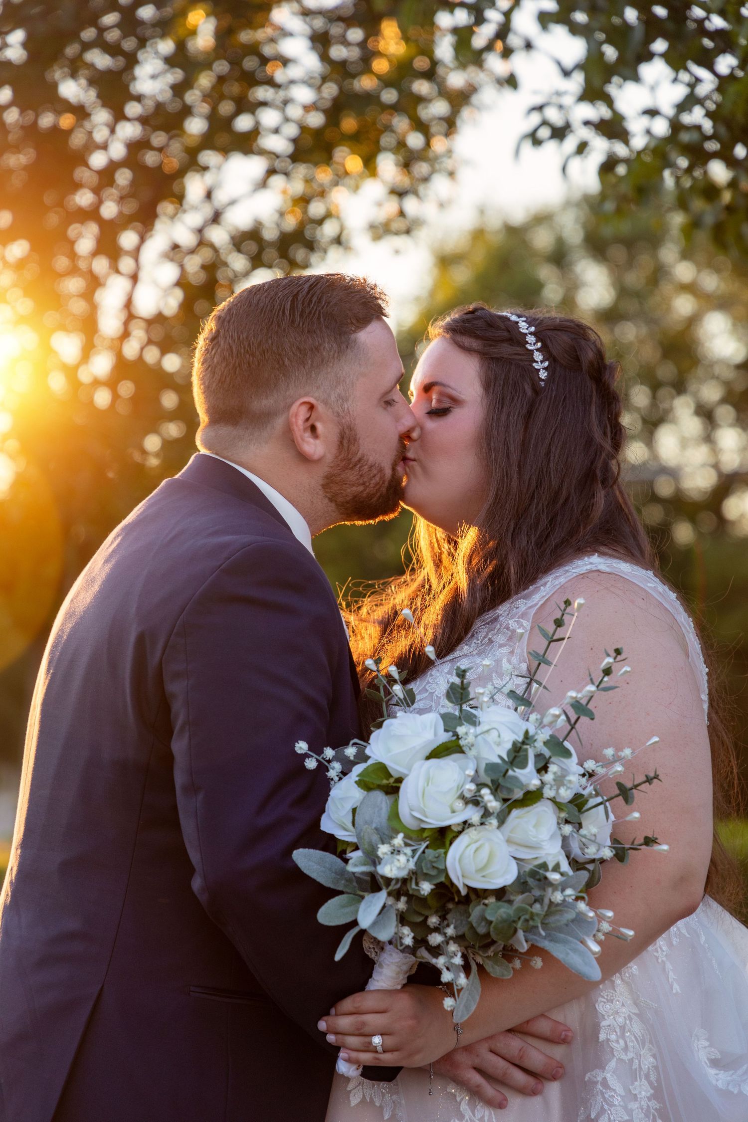 Sunset wedding portraits with couple holding white and green floral bouquet.