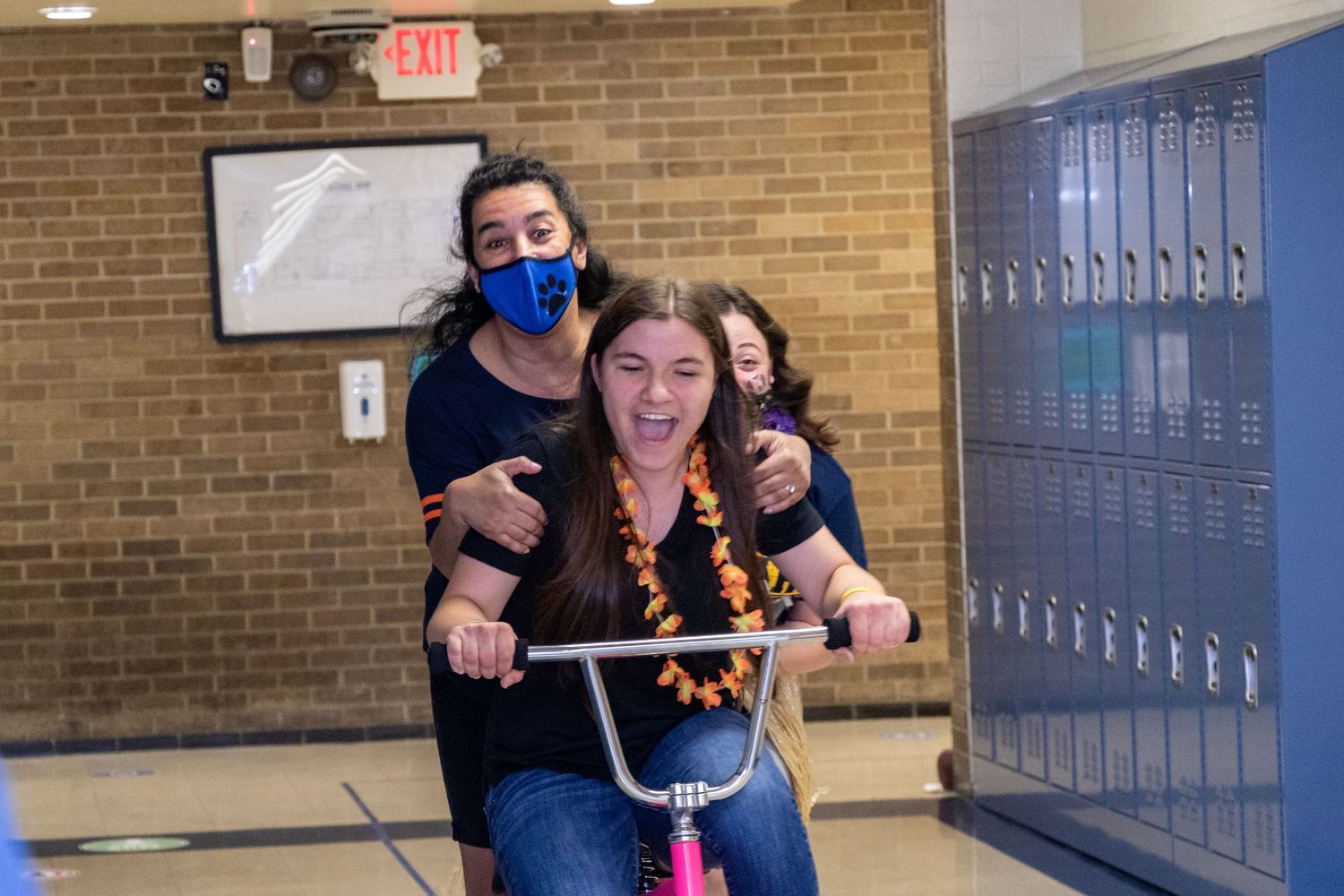 Students having fun and making silly faces in a school hallway with lockers.