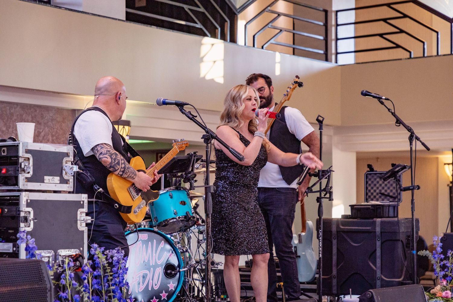Band performing on stage with guitars and musical equipment at indoor venue.