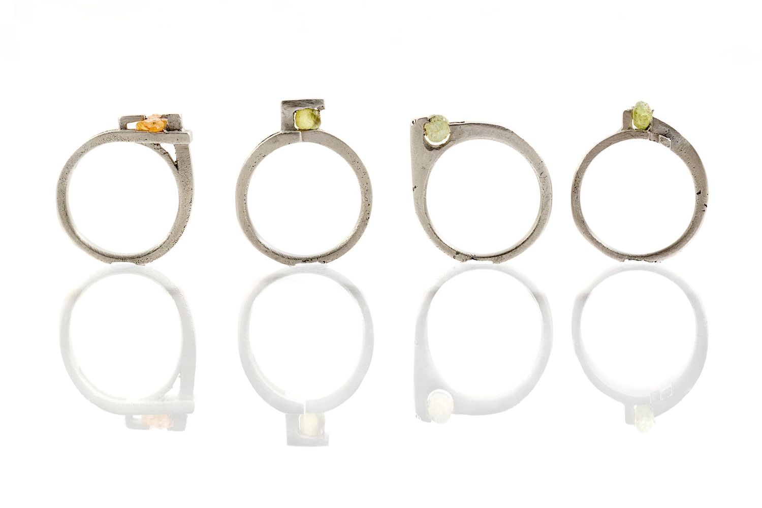 Collection of silver and gold wedding rings arranged in a row on white background.