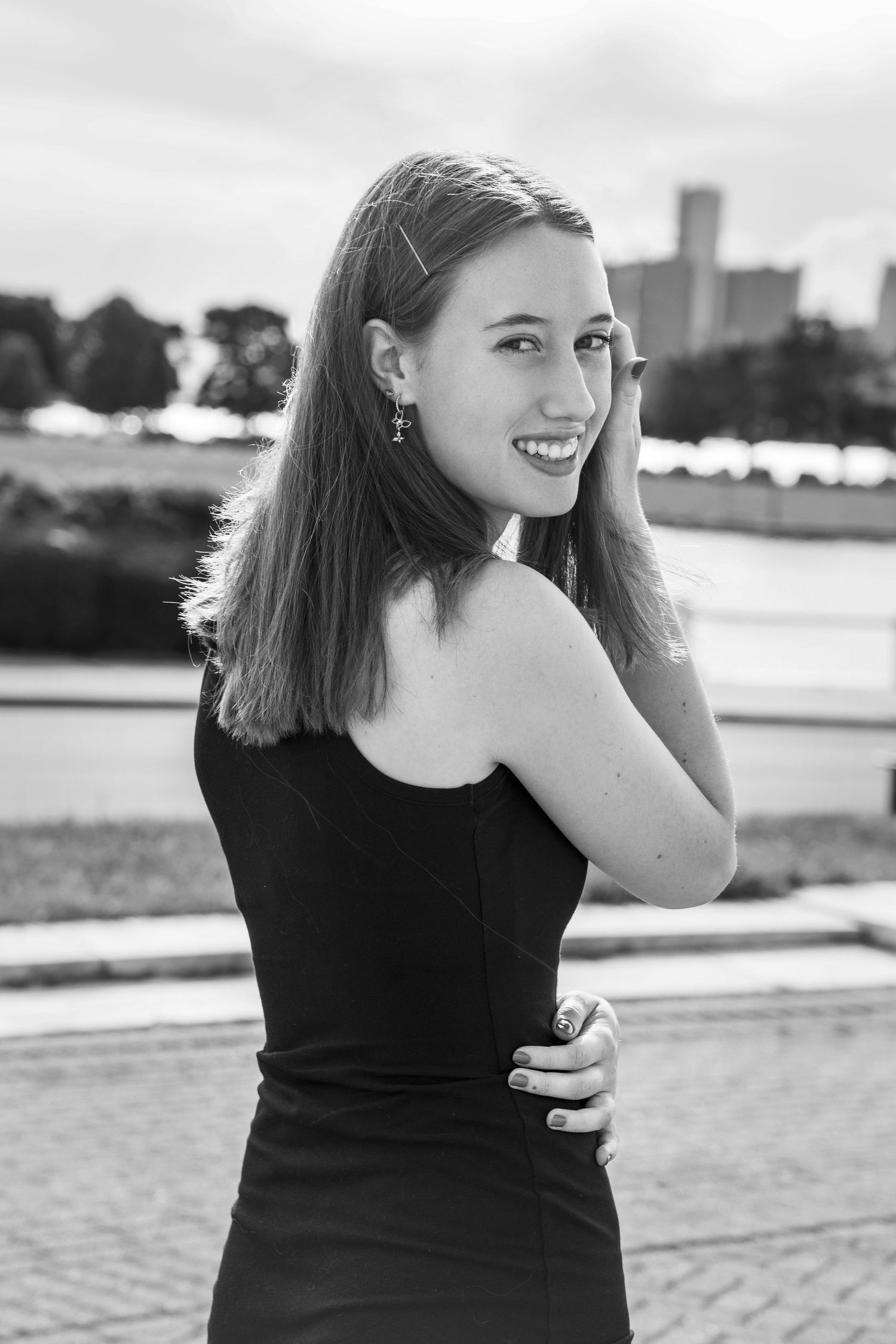 Black and white portrait series captured along a waterfront with city skyline in background.