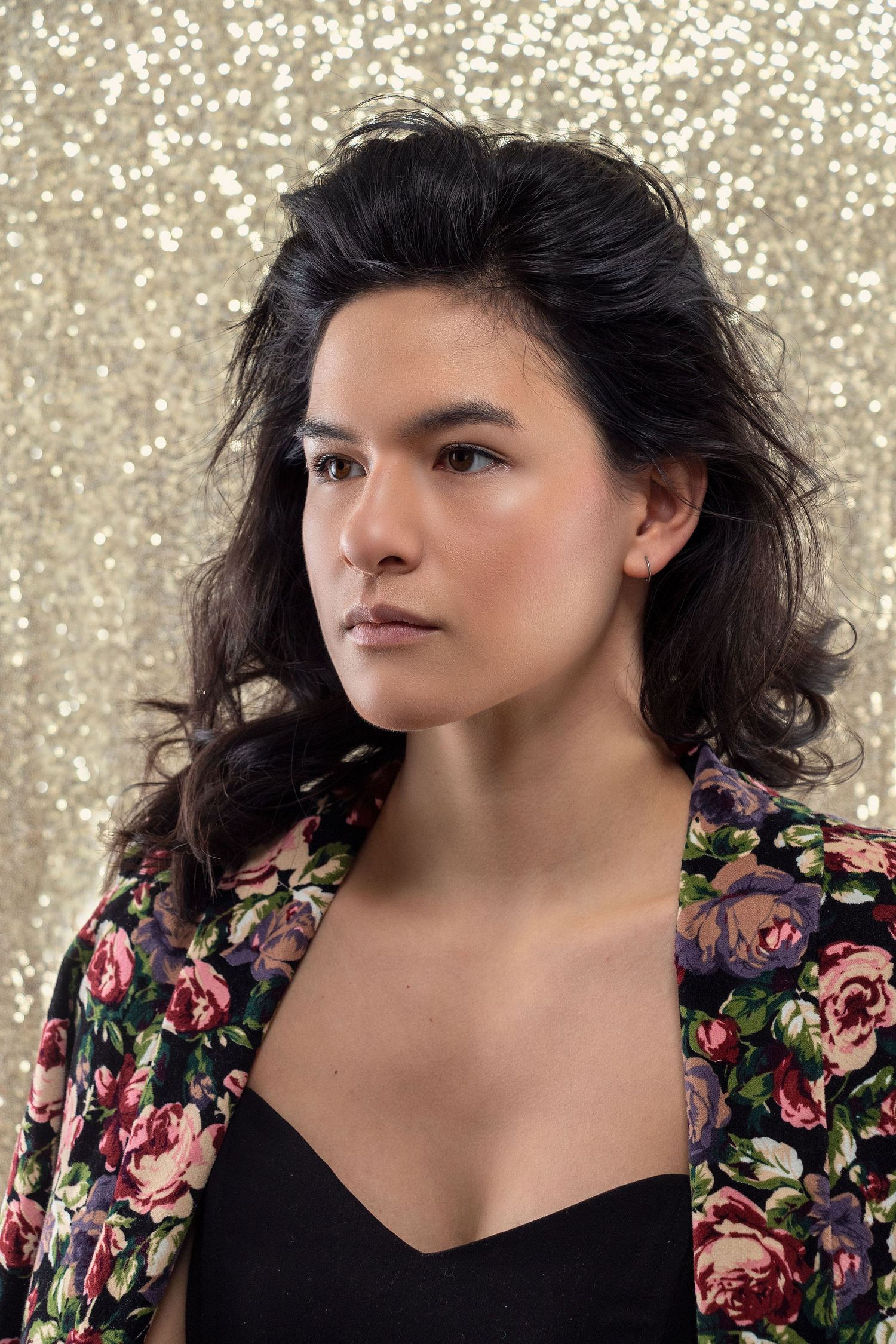 Close-up portrait series with dark hair against glittery background wearing floral print jacket.