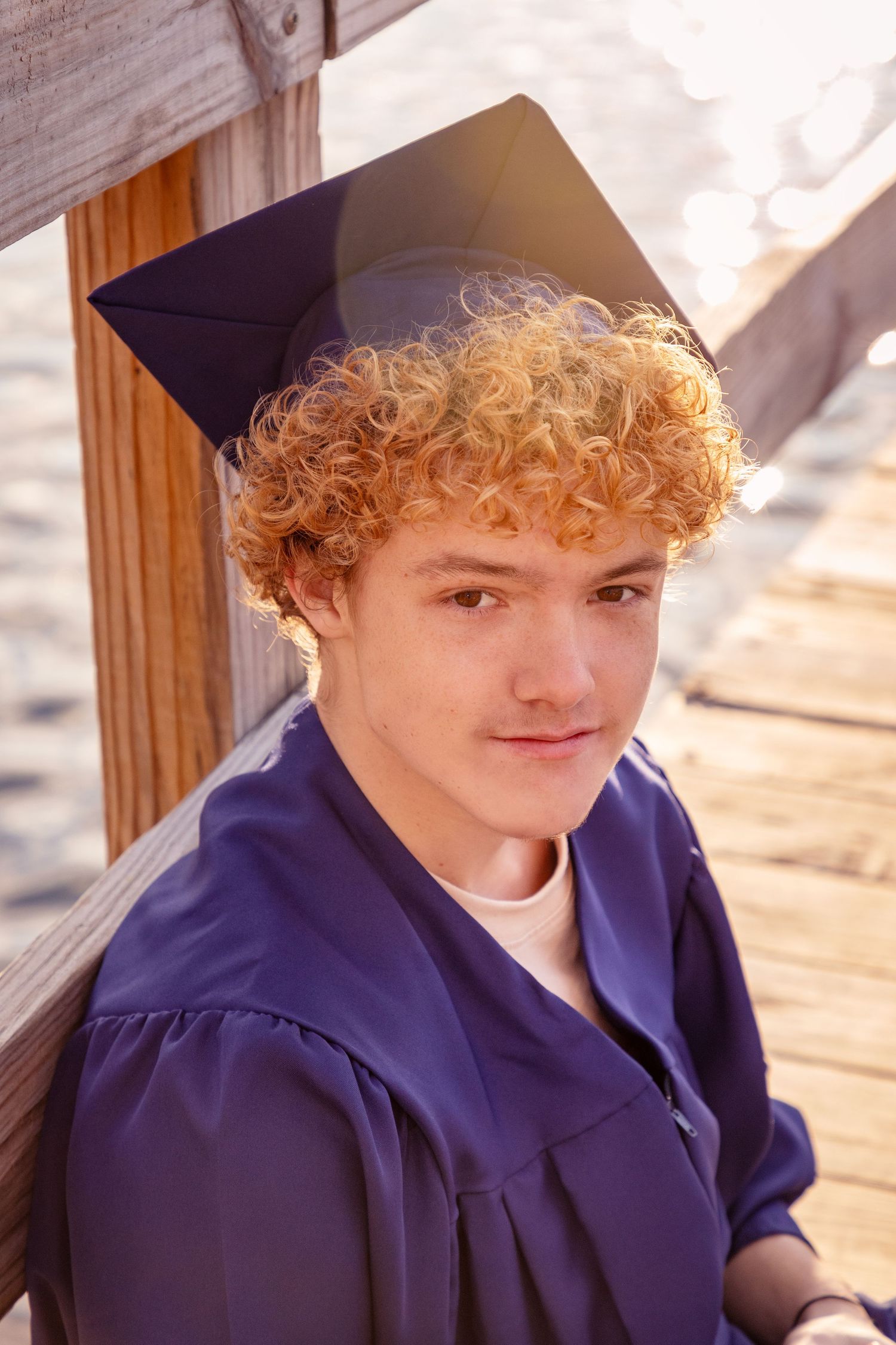 Graduate in navy blue cap and gown poses for graduation photos outdoors.