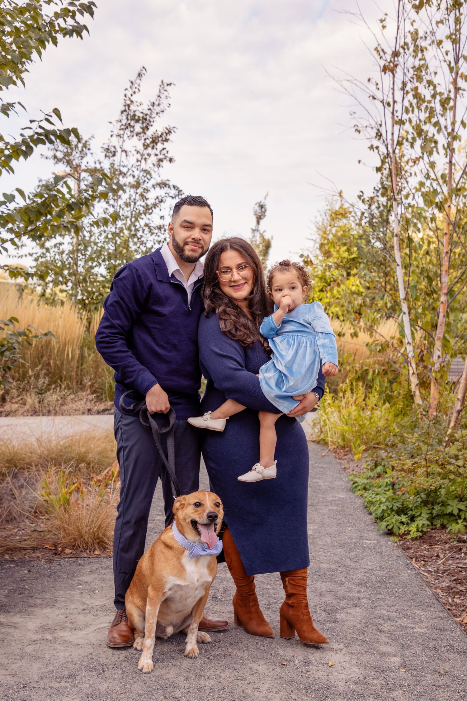 Family and dog posing together on nature trail during fall season photoshoot.